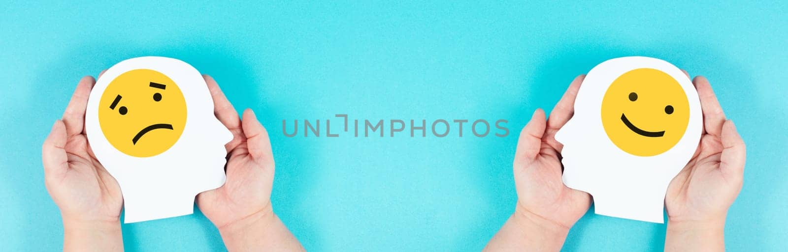 Holding a head with a sad and a happy face in the hands, mental health concept, positive and negative mindset, depression, support and evaluation symbol, emotion