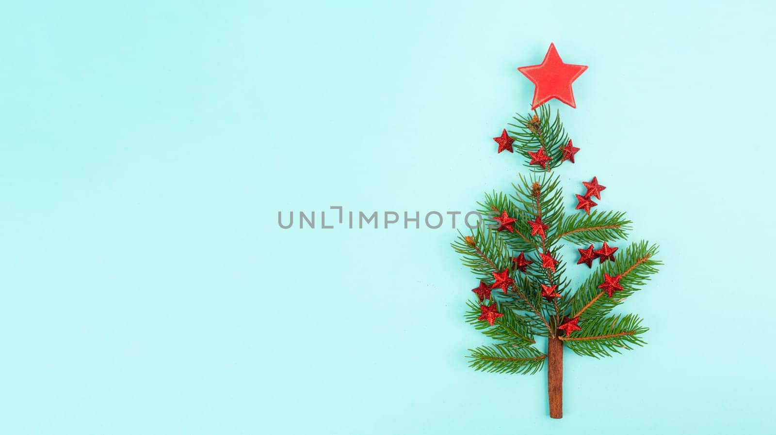 Christmas tree made from fir branches, red stars and a cinnamon stick as the trunk, greeting card with copy space