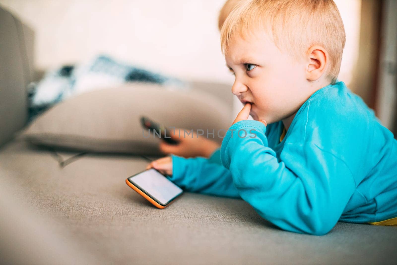 Little Caucasian Boy Playing Games On Phone Thoughtfully.