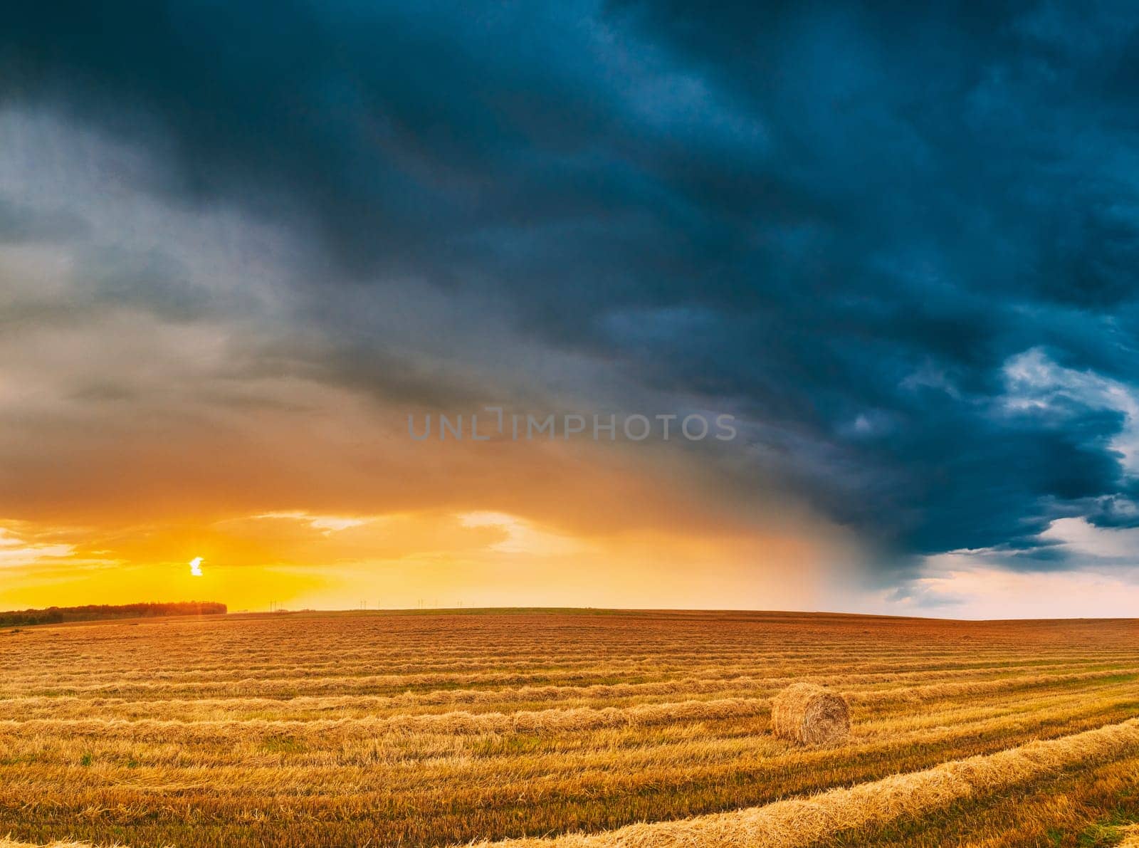 Aerial View Of Sunset Bright Sky Above Summer Hay Field Landscape In Evening. Haystack, Hay Roll in Sunrise Sunset time.