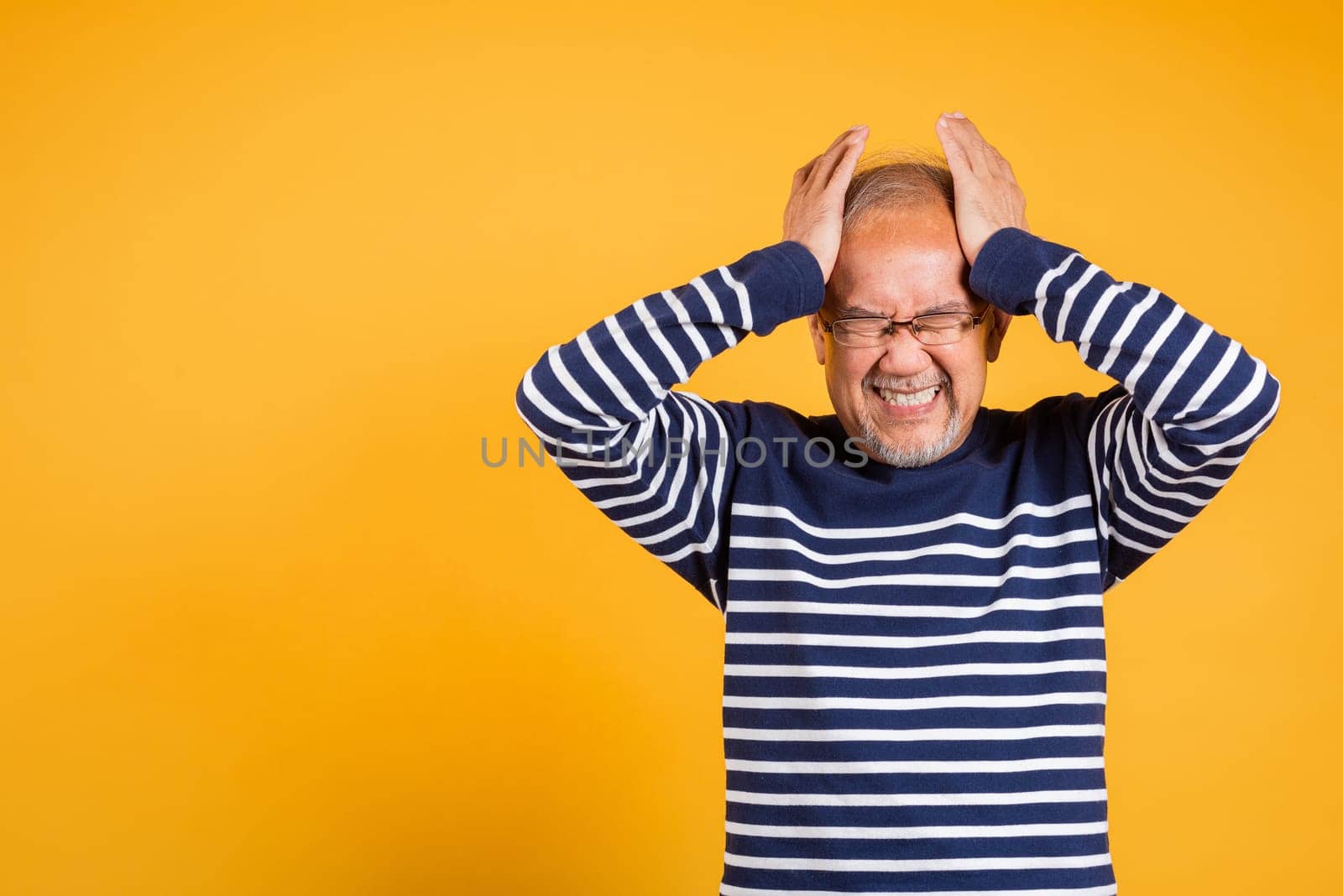 Asian elder man hands holding head and close ears suffering from headache studio shot isolated on yellow background, Portrait senior old man sad suffering from migraine, depressed health care