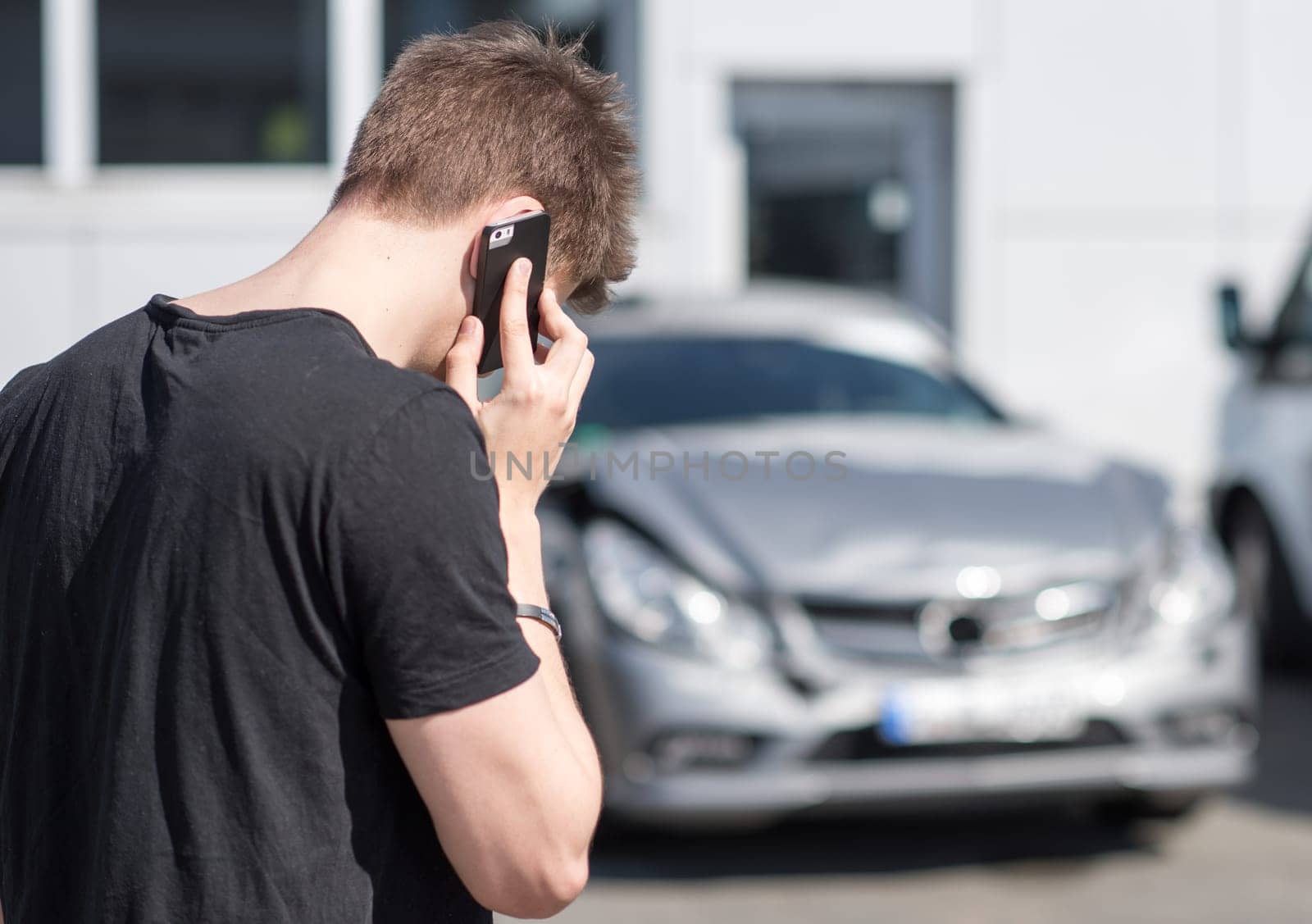 Young man on the phone after car crash