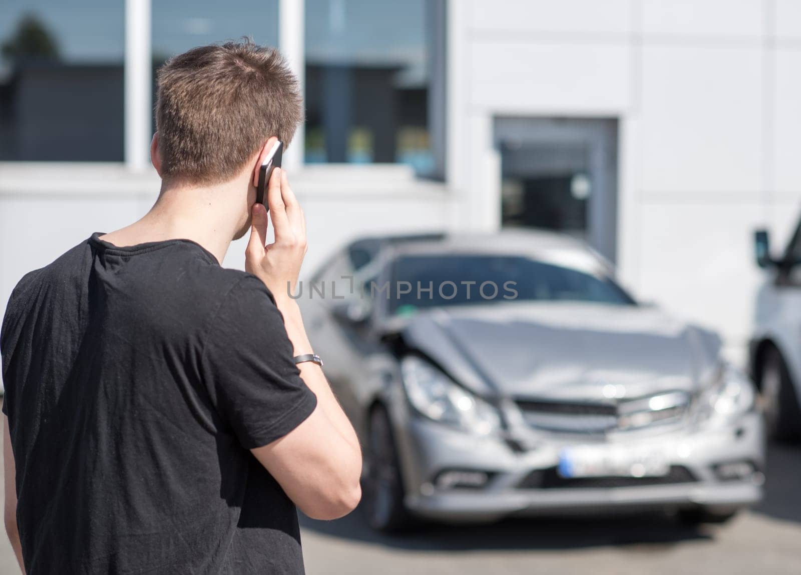 Young man on the phone after car crash