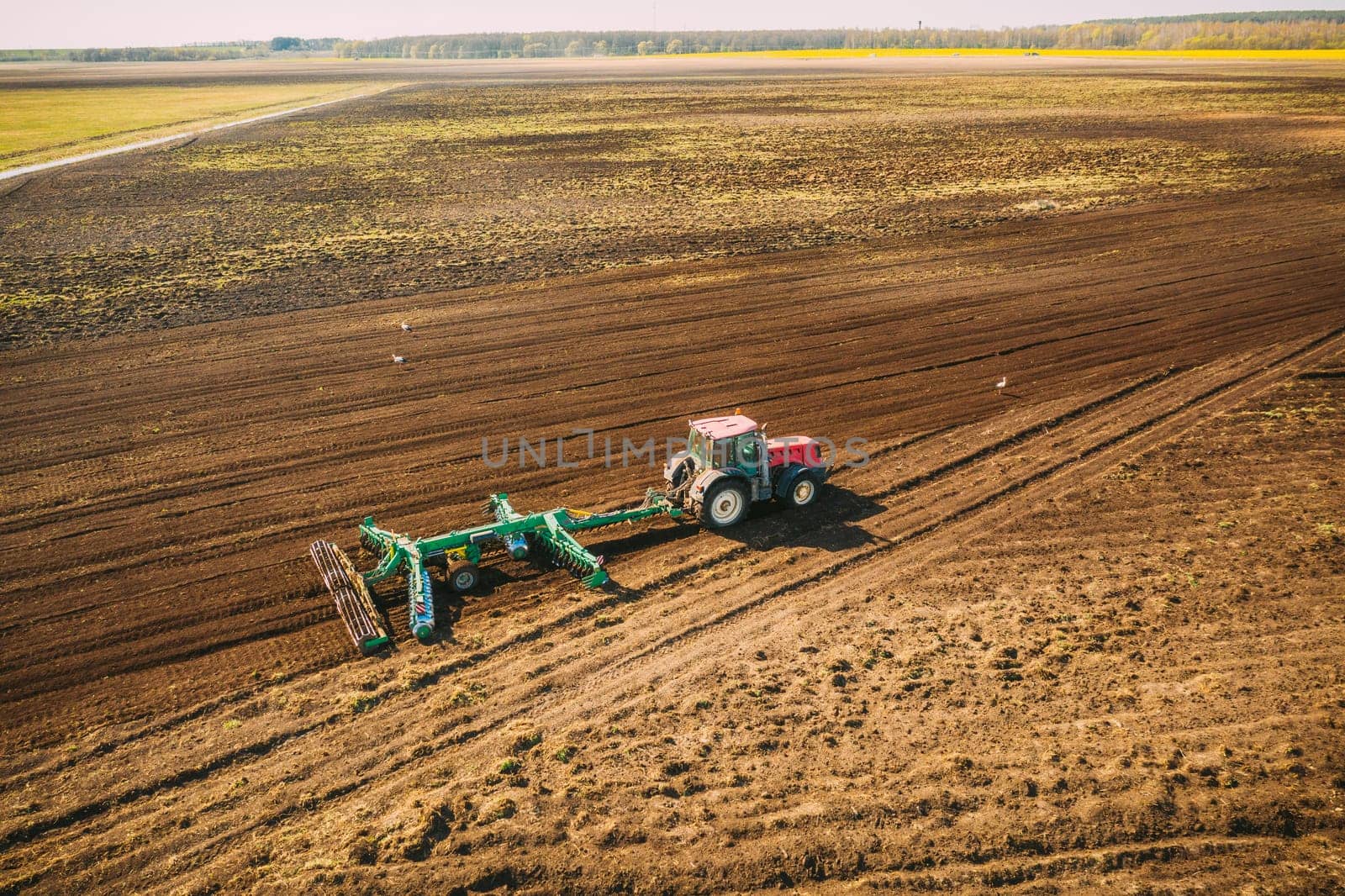 Aerial View. Tractor Plowing Field. Beginning Of Agricultural Spring Season. Cultivator Pulled By A Tractor In Countryside Rural Field Landscape.
