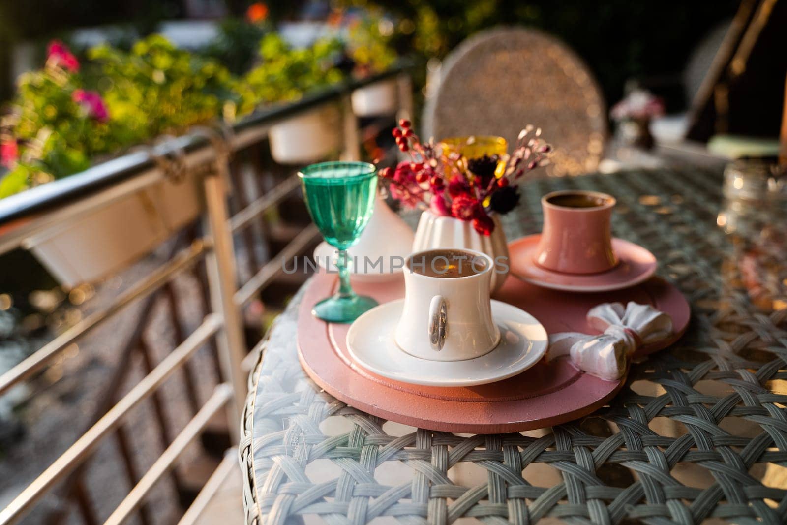 front view closeup of traditional Turkish coffee cups served outside with water flowers and delight dessert in romantic setup on glass table at sunset