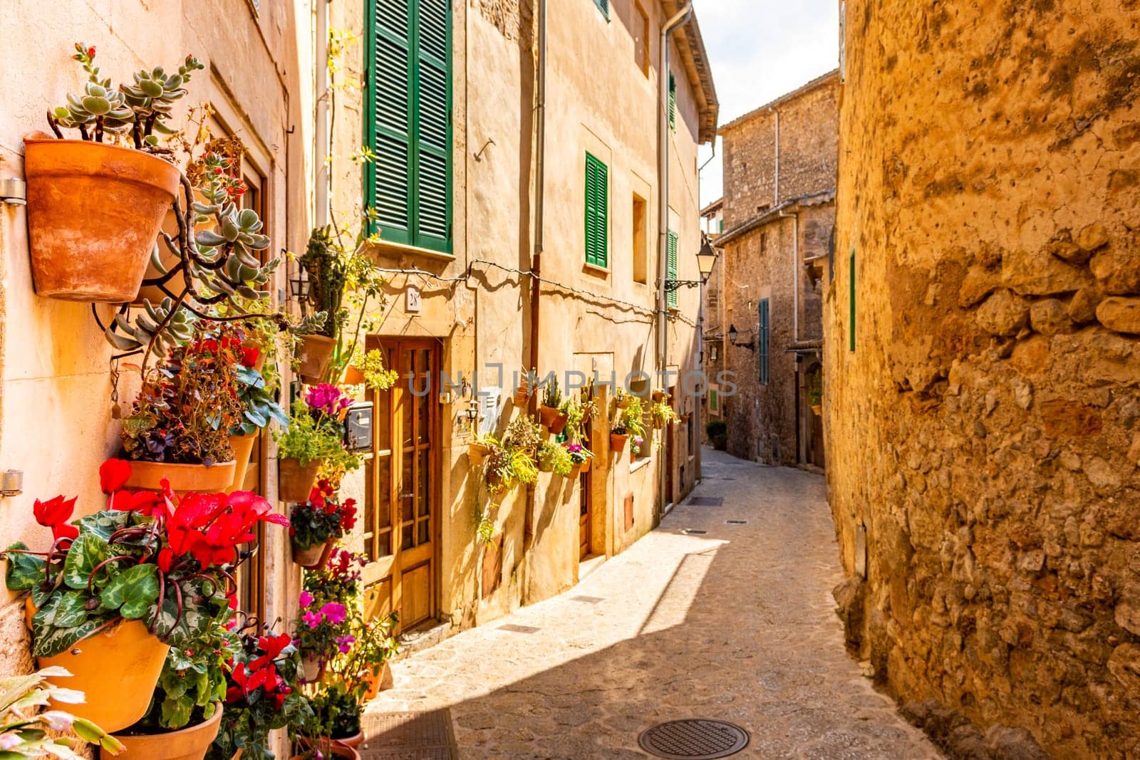 A view of internal sunny passage of decorated doors and old floor in valldemossa, Mallorca, Spain