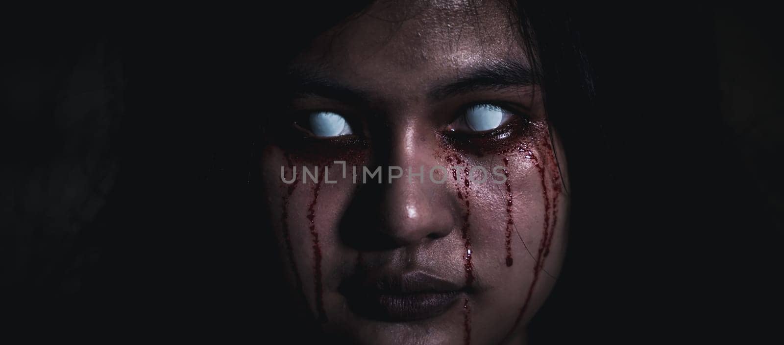 Bloody halloween makeup. Close up of horror bloodthirsty ghost female with fade drop out from eyes, Asian woman with blood eye she death and scary with blood tear on face, Happy halloween day concept