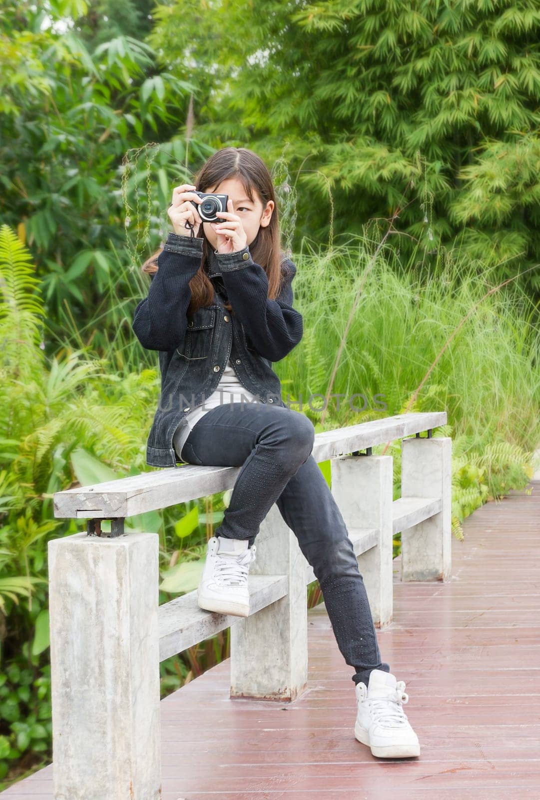 Beautiful Asian young girl taking photos outdoors in green park