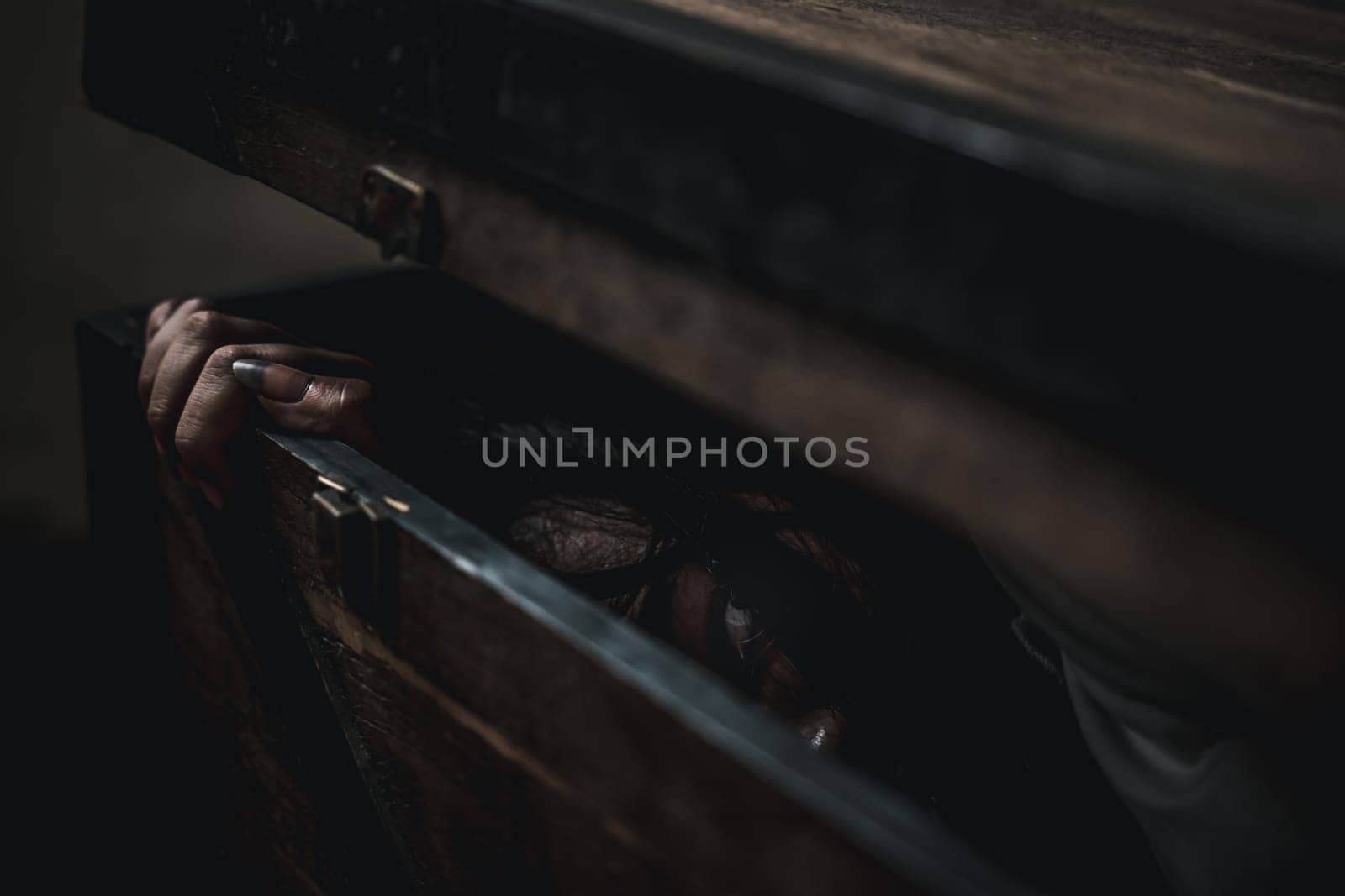 Horror ghost woman. Asian ghost horror creepy scary hair covering face and eye lying in the old treasure chest she look at camera, female makeup terror zombie face, murder, Happy Halloween day concept
