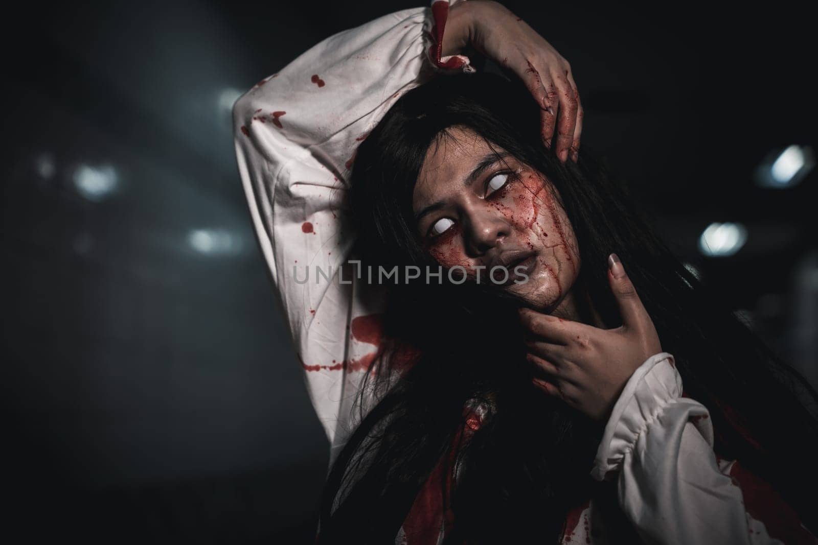 Screaming zombie female face with blood grabs her head to twist it off, Horror bloodthirsty woman ghost or zombie she is horror scary with breaks her neck at dark night, Happy halloween day concept