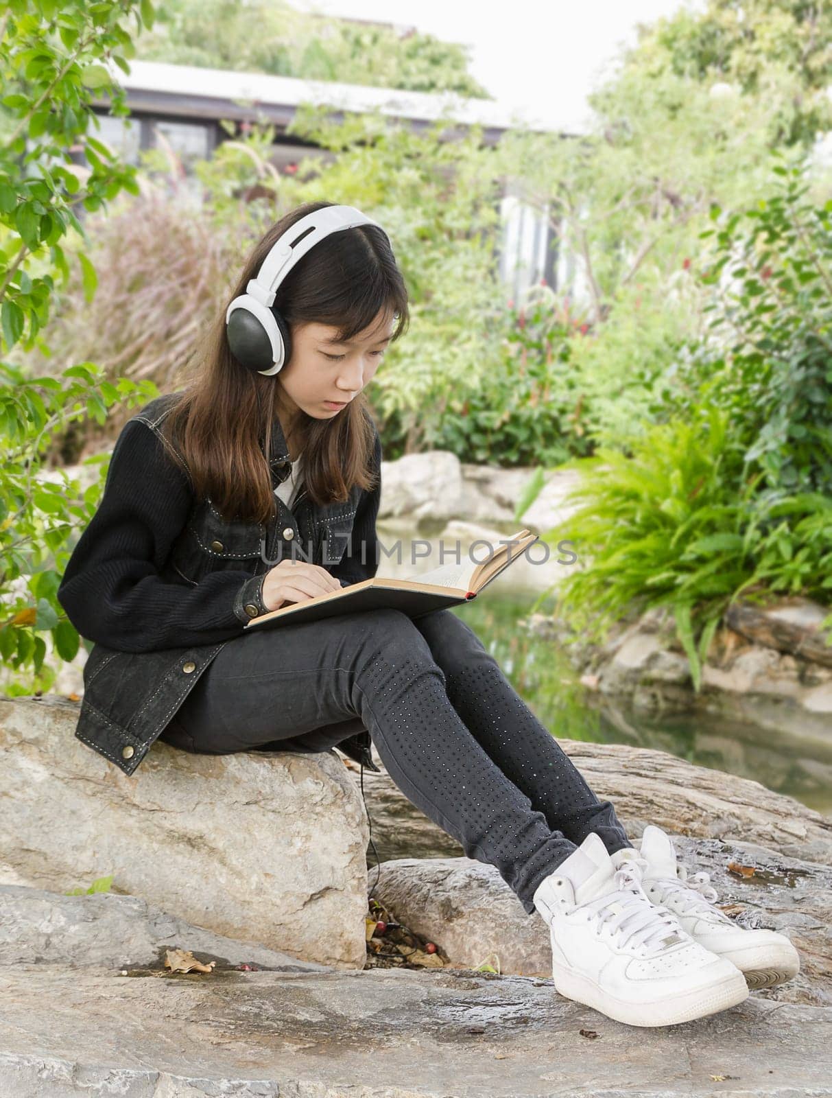 Young beautiful girl reading a book and .listen to music at the park