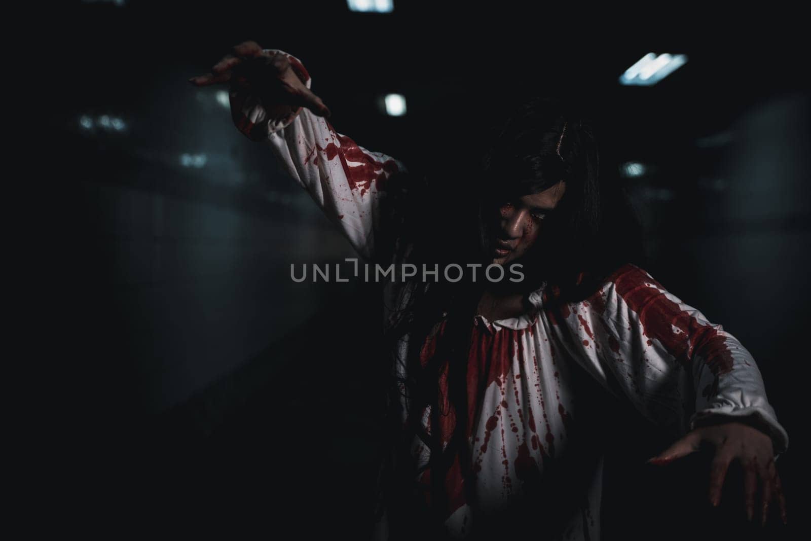 Bloody halloween makeup. Horror bloodthirsty ghost girl hair covering face and eye reach arm out, Asian woman zombie with blood she death and scary at night in tunnel, Happy halloween day concept