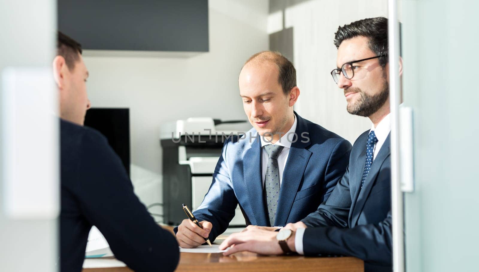 Team of confident successful business people reviewing and signing a contract to seal the deal at business meeting in modern corporate office. Business and entrepreneurship concept.