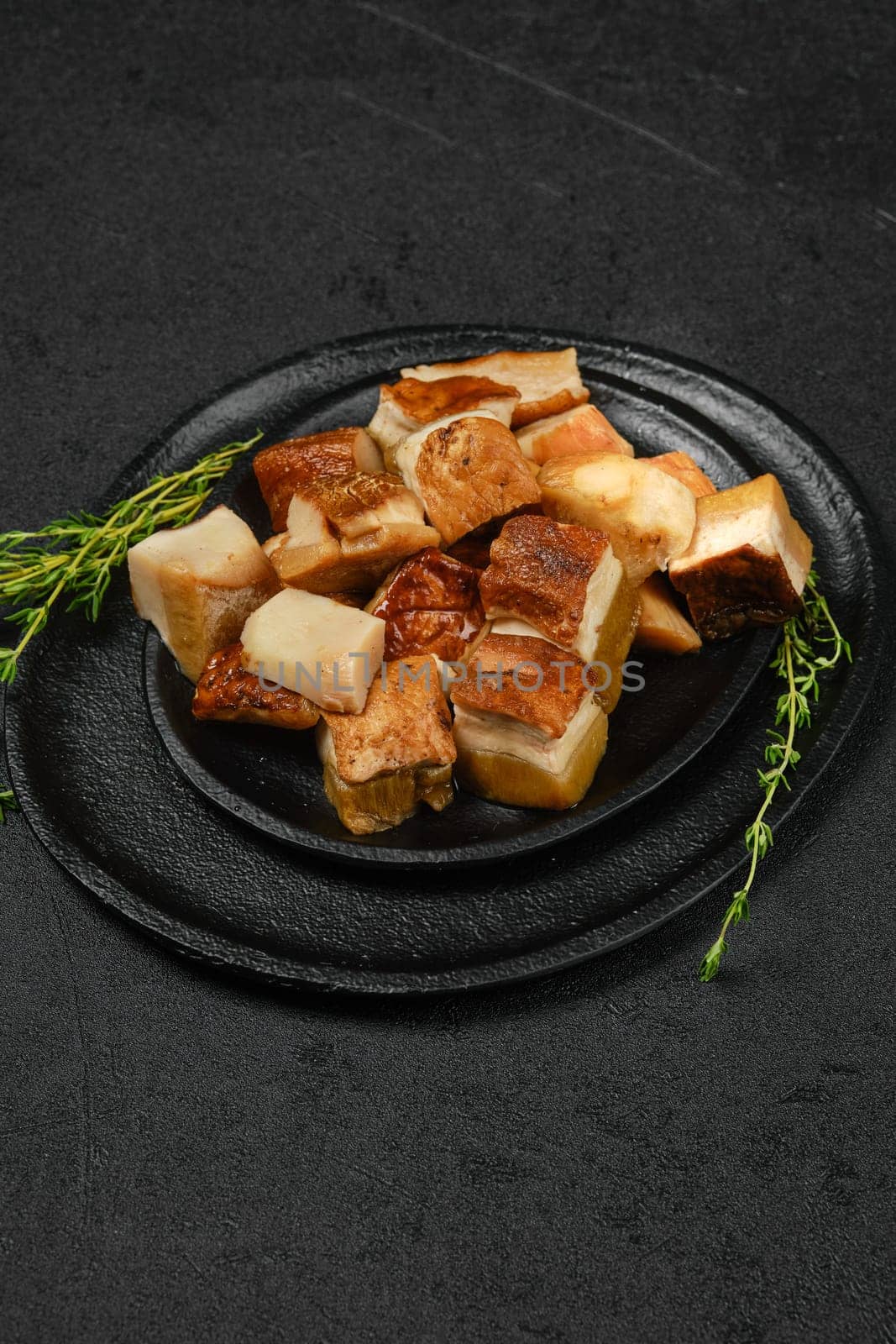 Frozen fresh boletus cut on pieces on black stone plate
