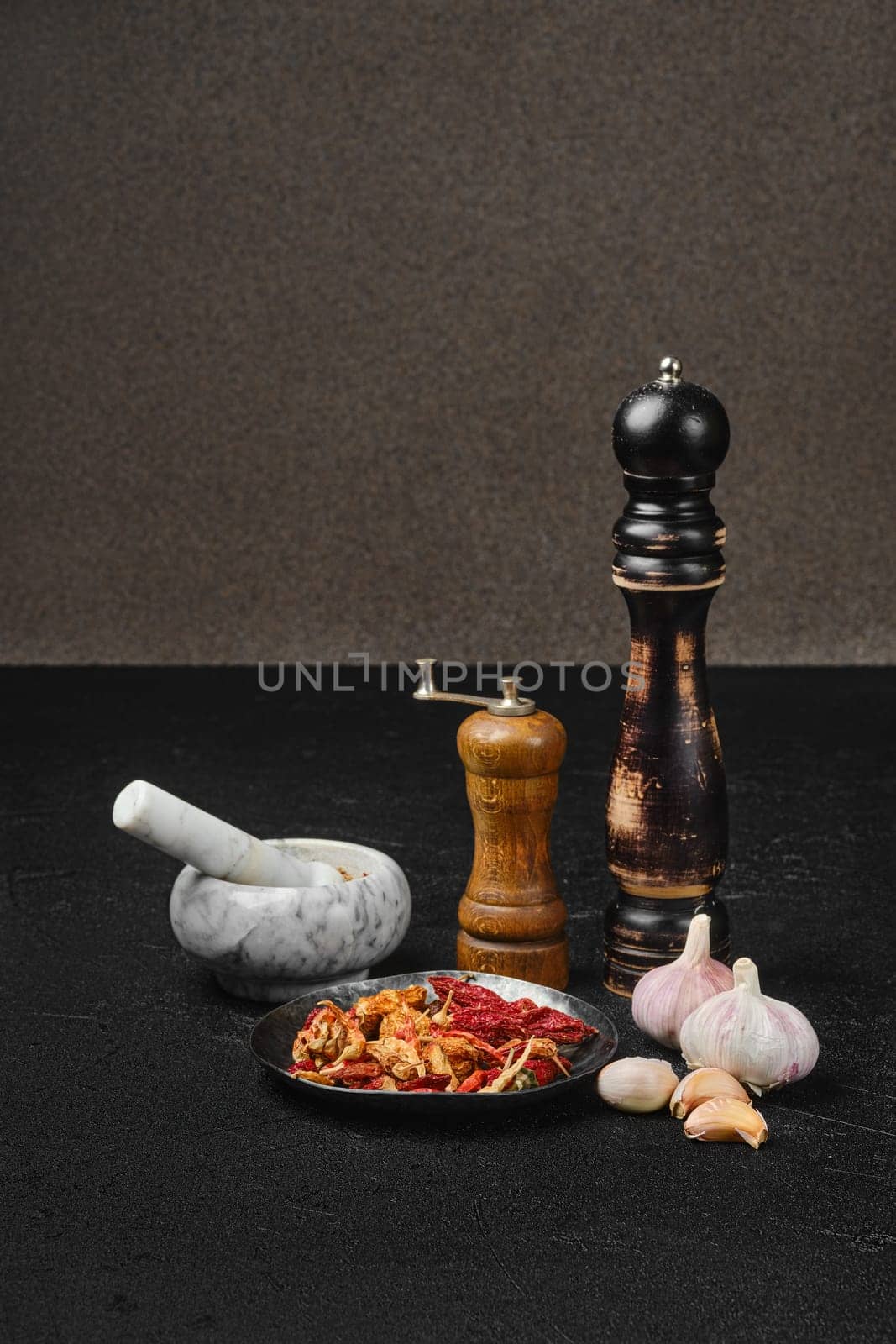 Spice mortar, mill and grinder on a table with fresh garlic and dry chilli pepper