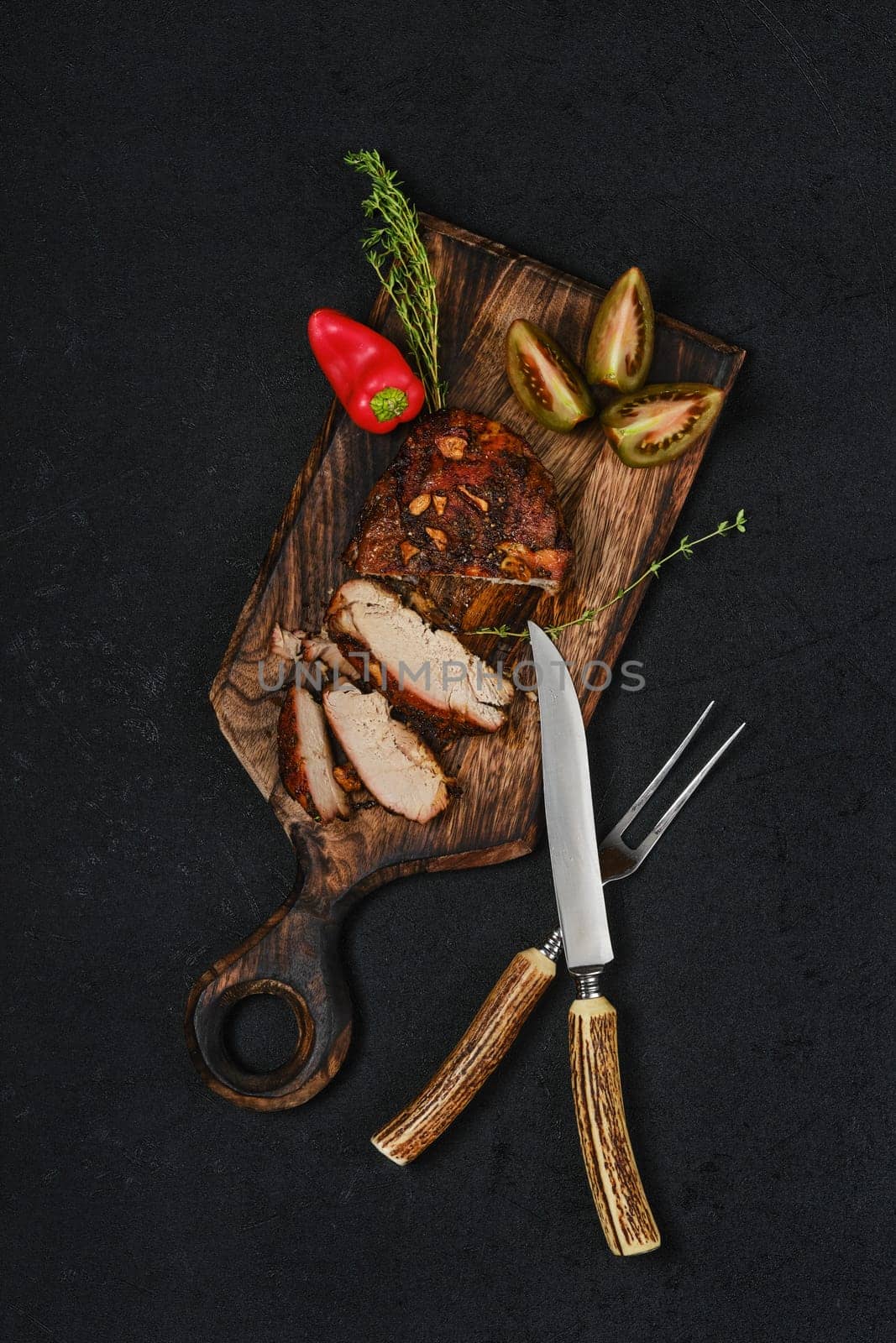 Overhead view of baked in oven pork fillet on wooden serving board