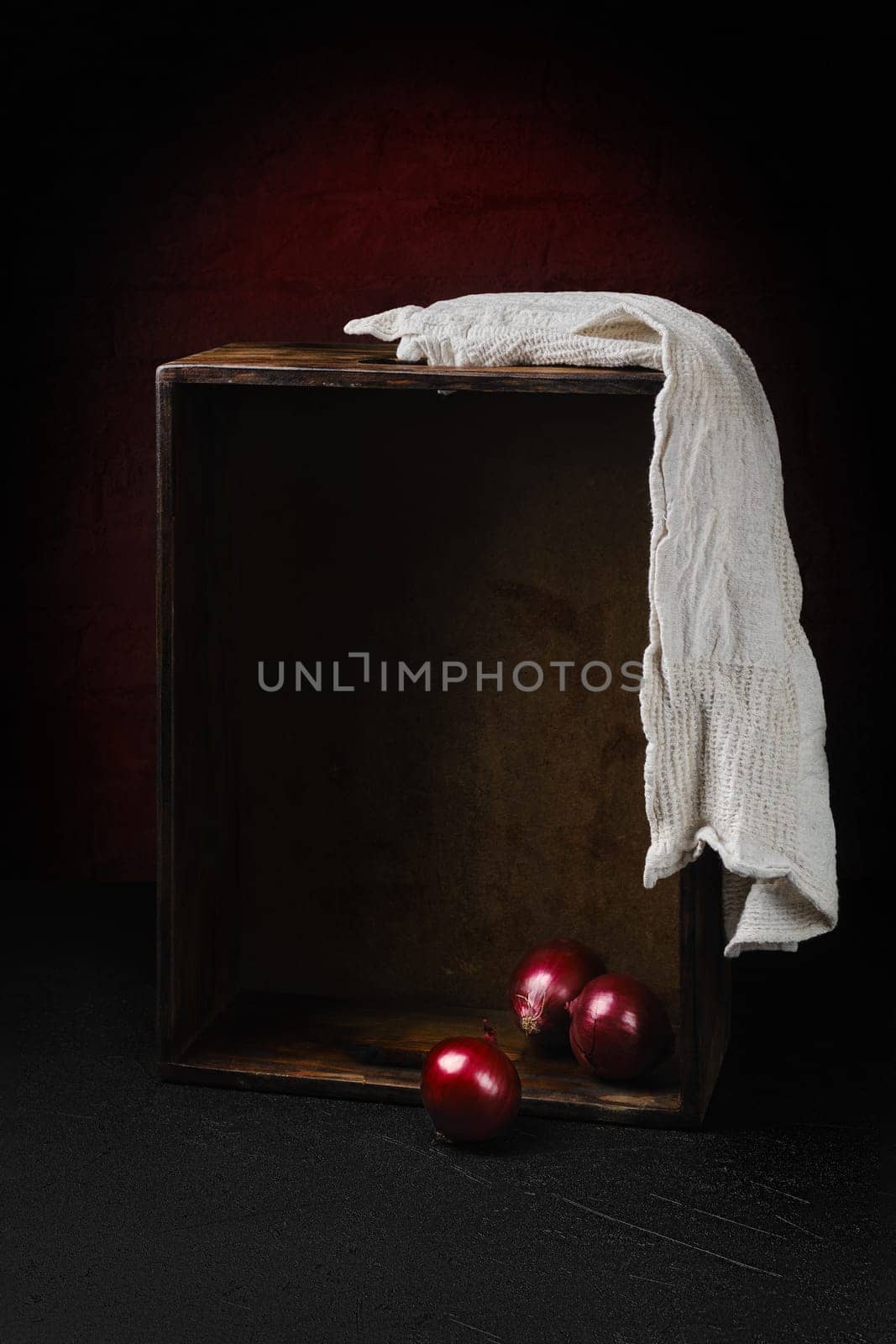 Low key photo of empty wooden box and three onions