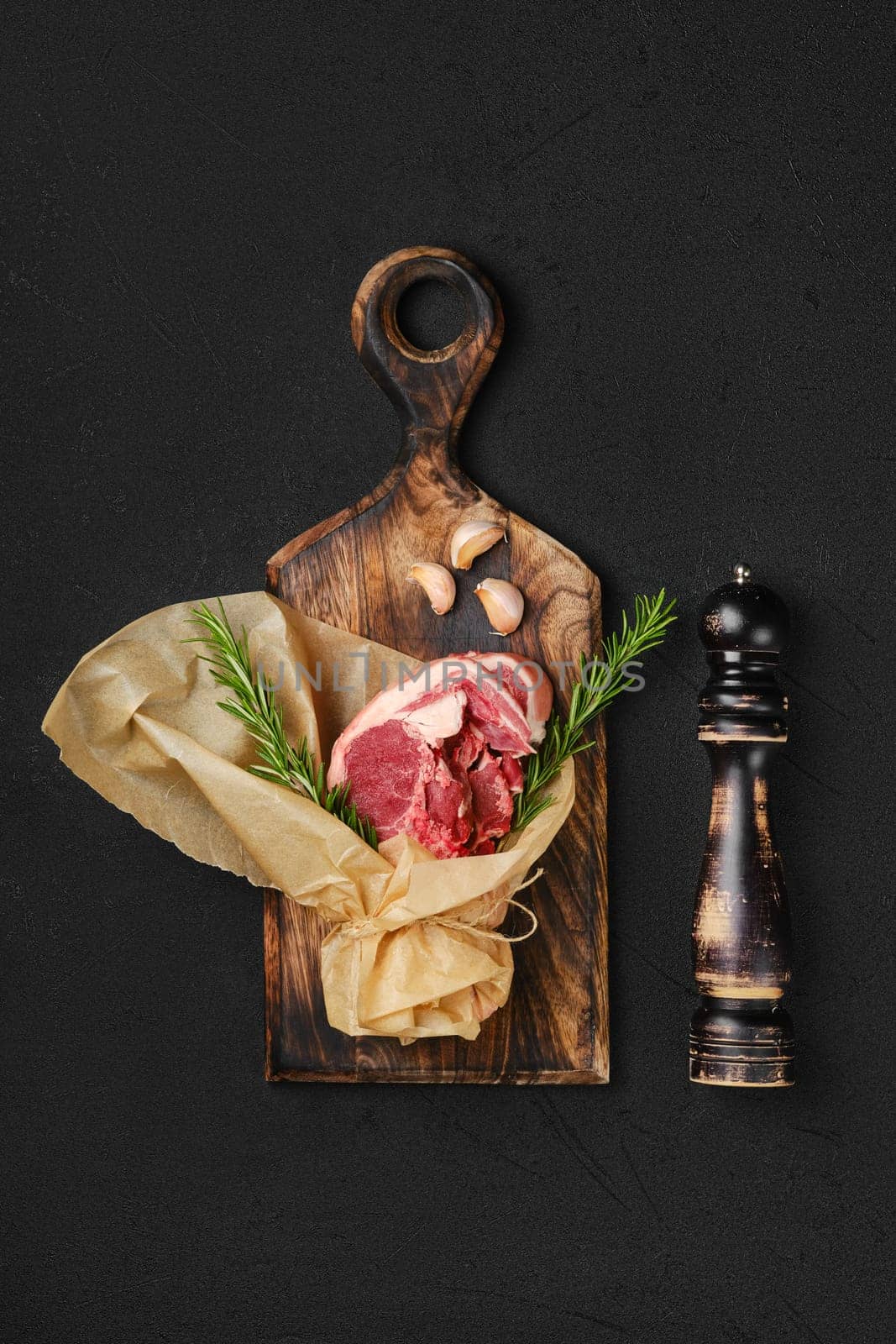 Raw fresh lamb double loin chop wrapped in paper on wooden cutting board