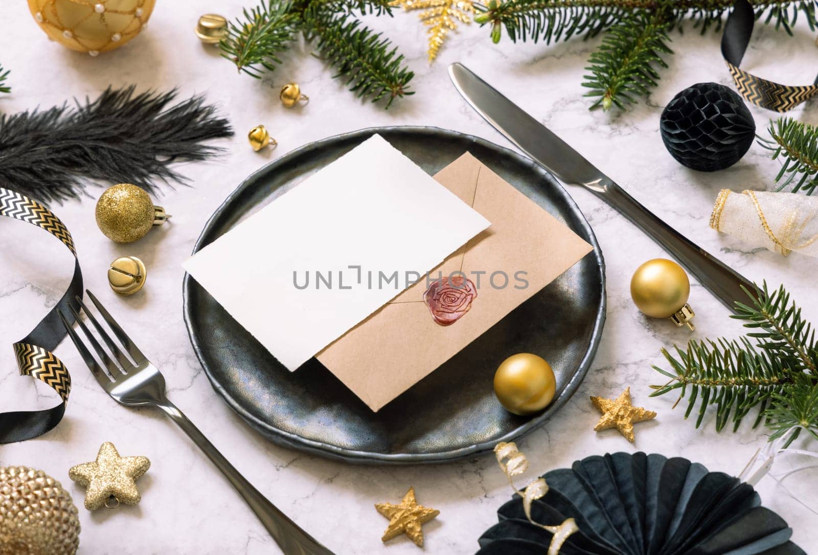 Black and golden Table setting with ornaments and fir tree branches close up, invitation card mockup. Christmas or New Year atmospheric composition on marble table, copy space.