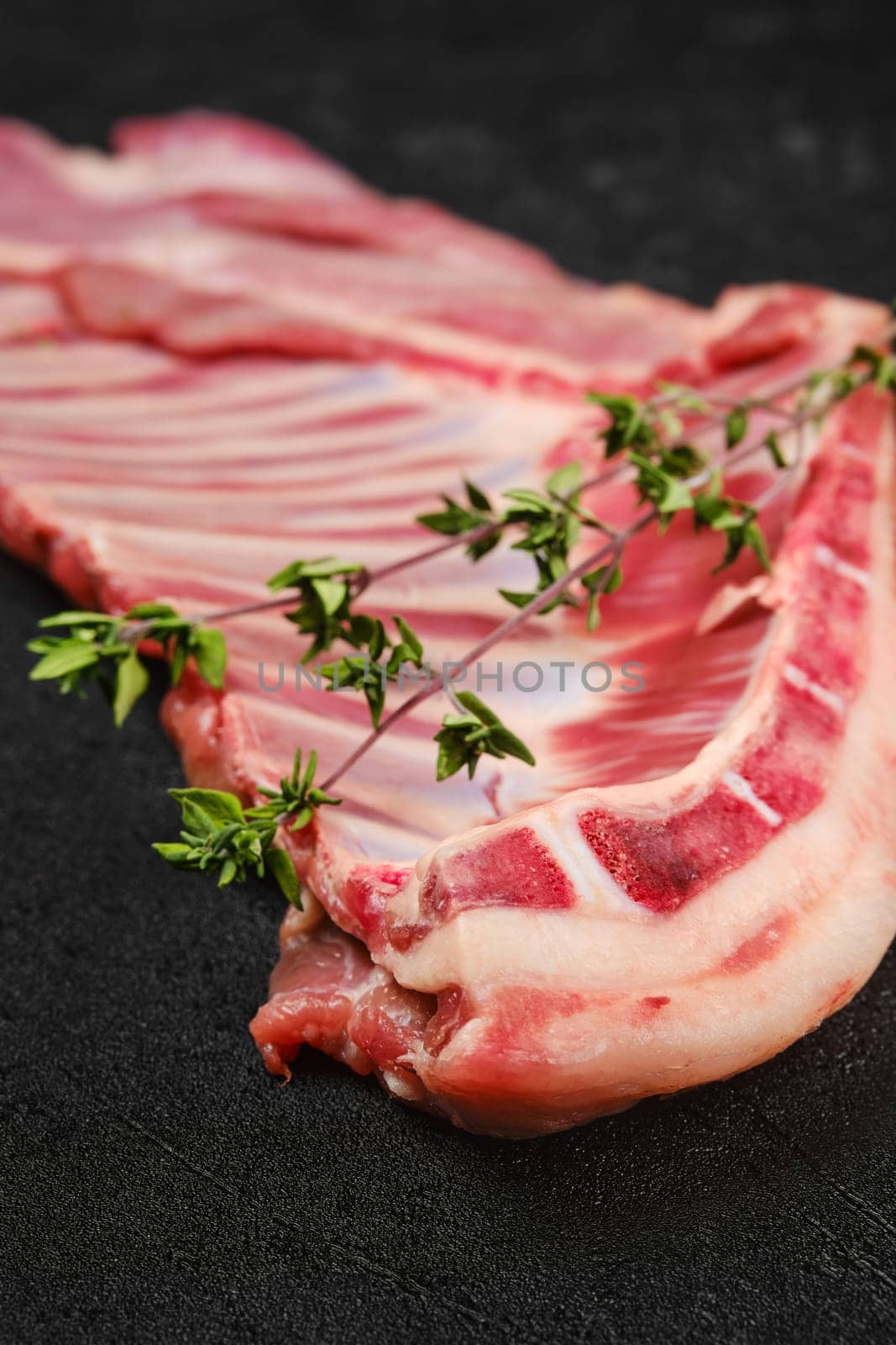Closeup view of raw fresh lamb ribs, uncut with spices and herbs