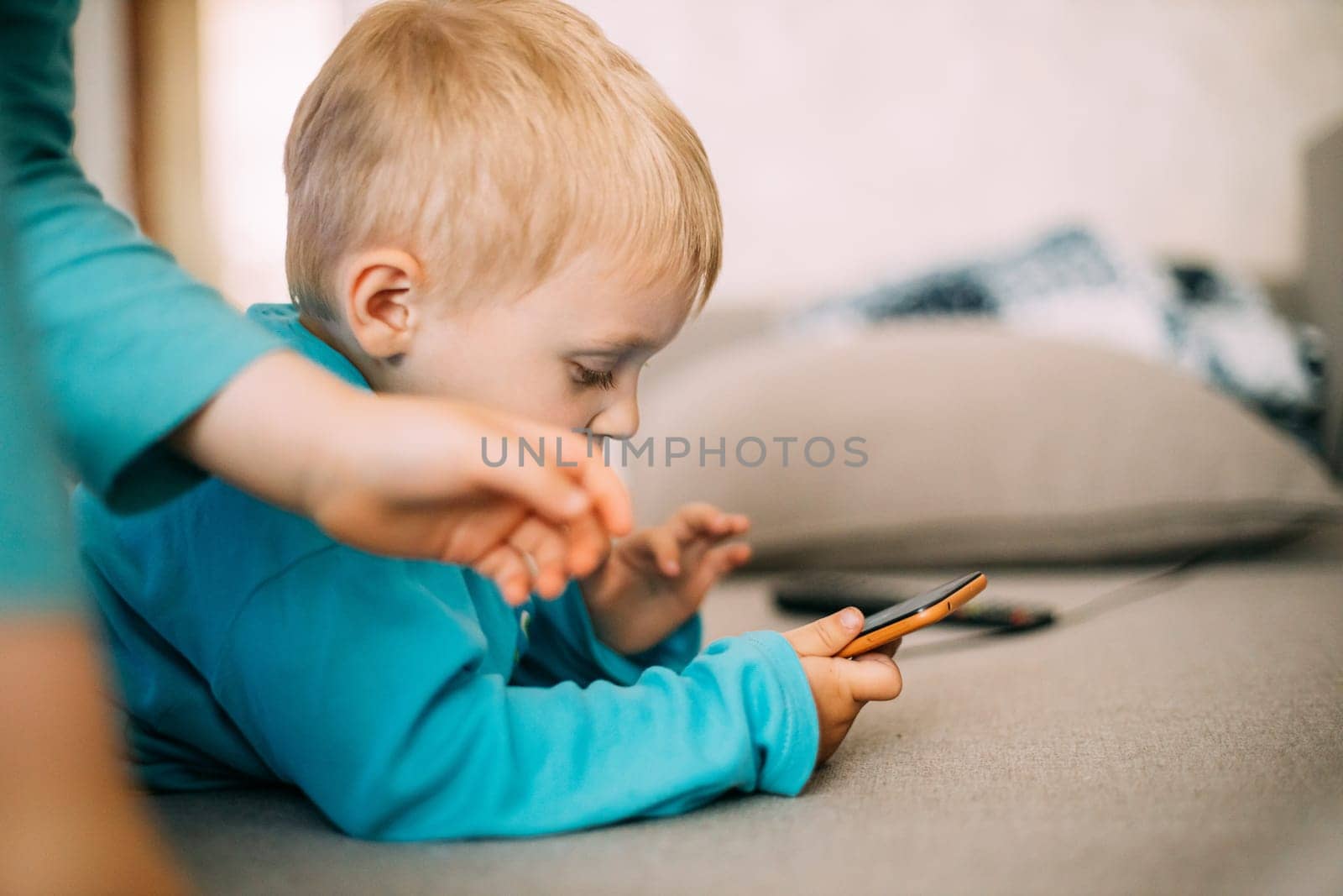 Caucasian Boy Playing Games On Phone Thoughtfully. The older child tries to take the phone from the younger brother.