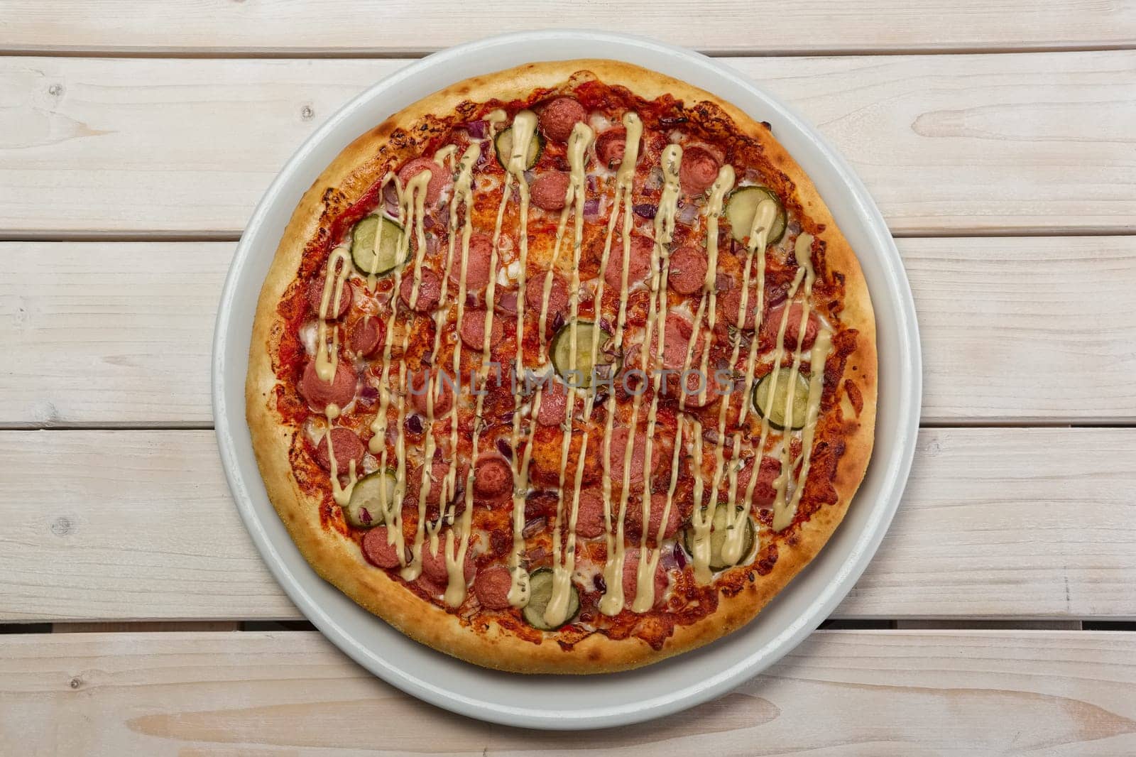 Top view of pizza with thin sausage and pickled cucumber