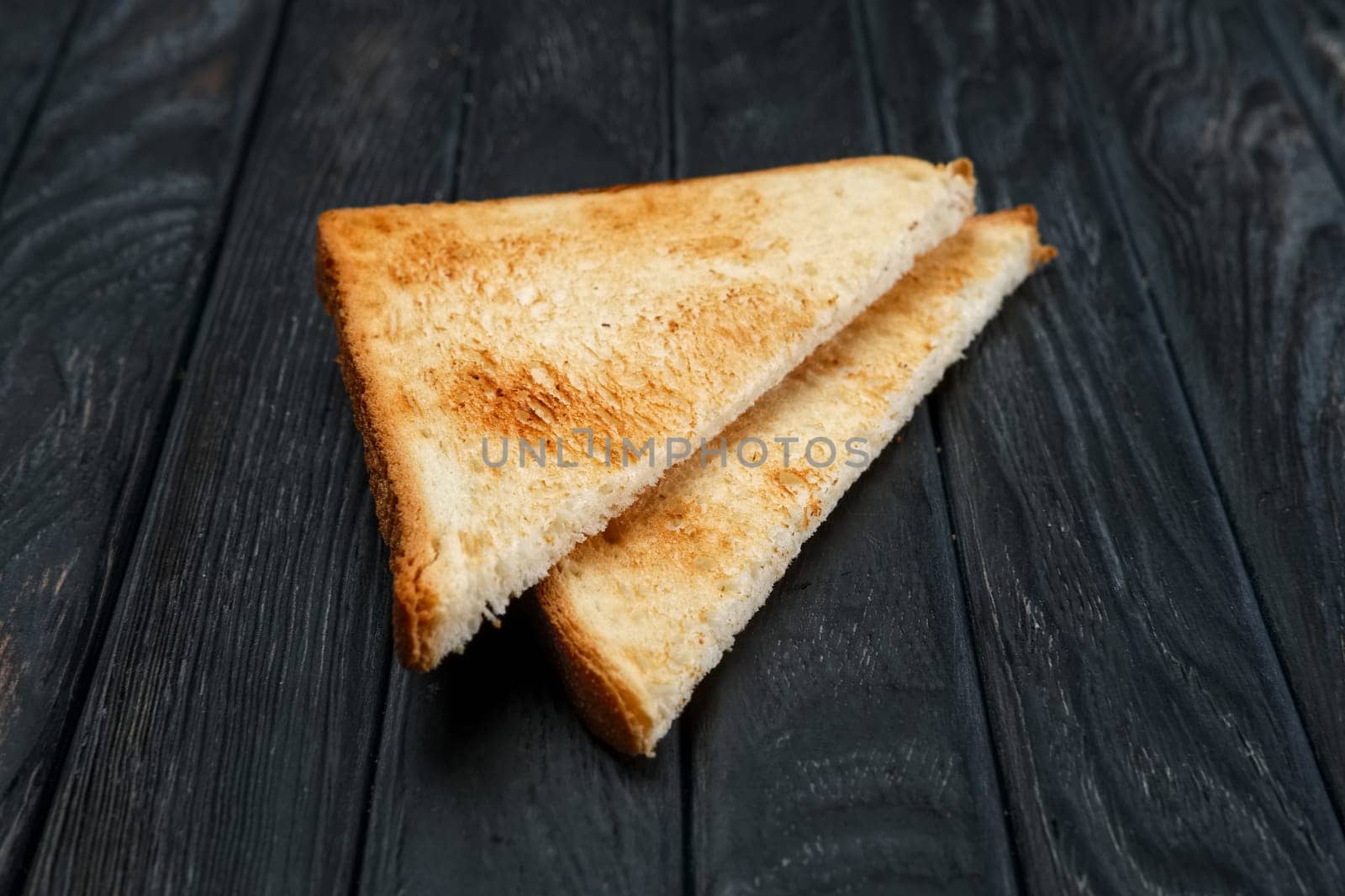 Two pieces of toast bread on dark wooden table. Top view.