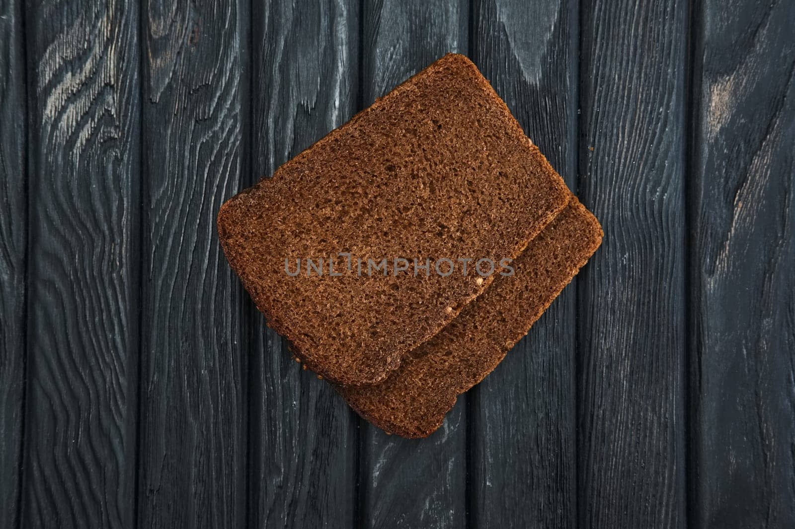 Two pieces of brown bread on dark wooden table. Top view.