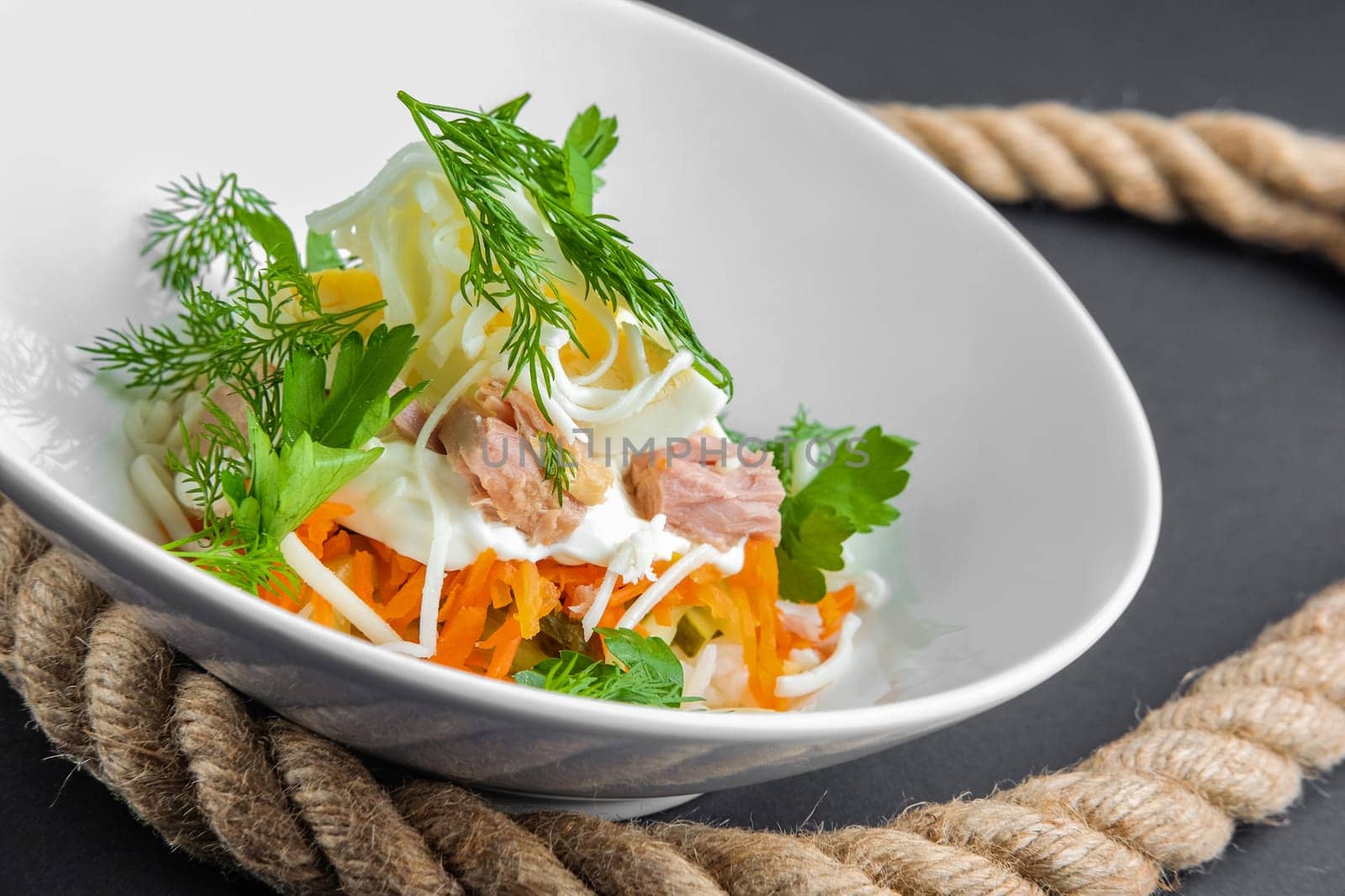 Plate with tuna salad with eggs, carrot, onion and mayonnaise, closeup