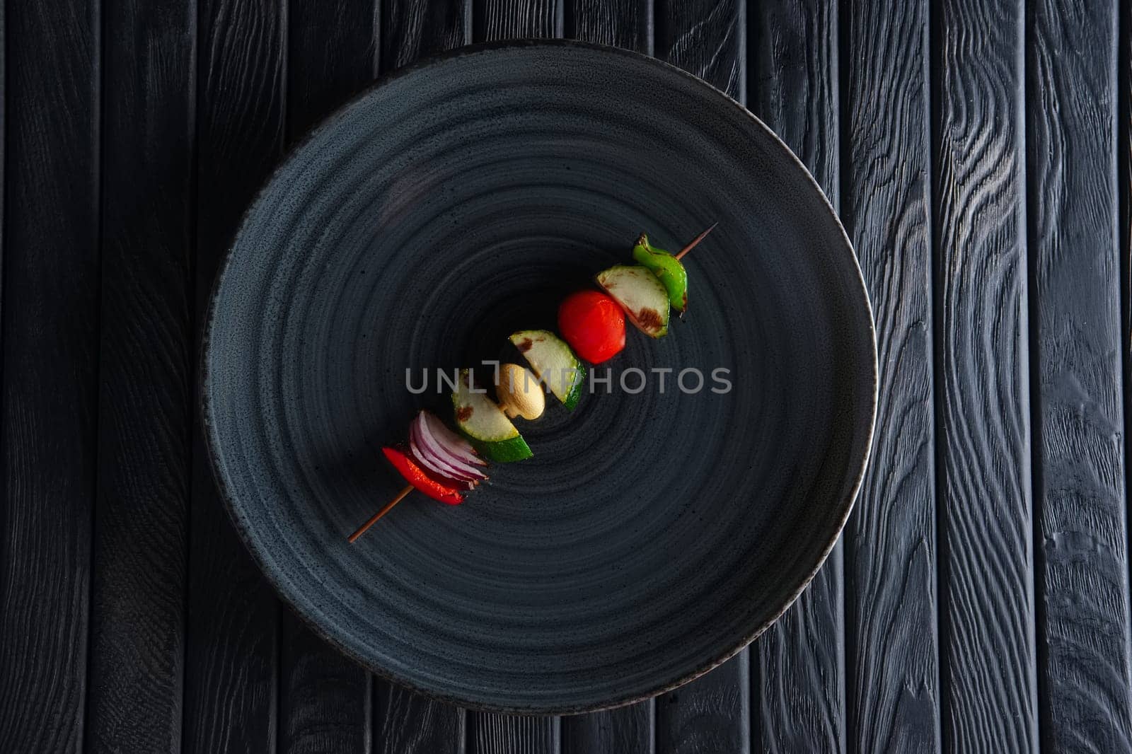 Top view of grilled zucchini, bell pepper, mushroom, tomato and onion on skewer