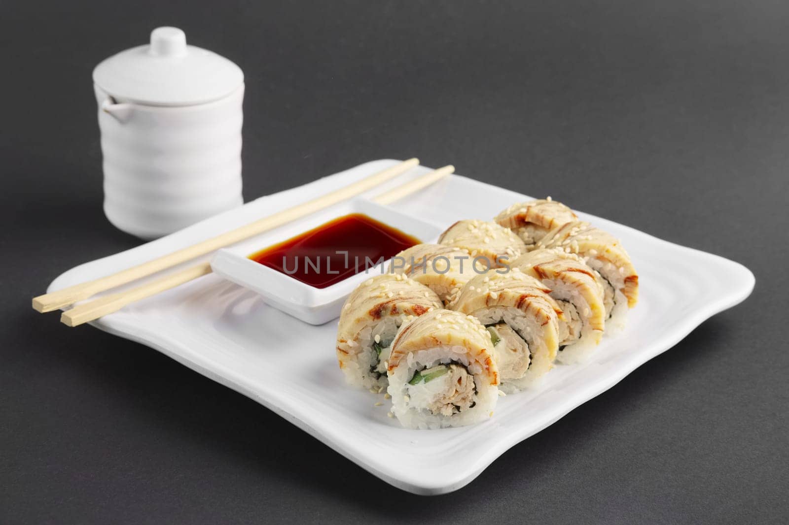 chicken teriyaki roll with chopsticks and soy sauce on a plate