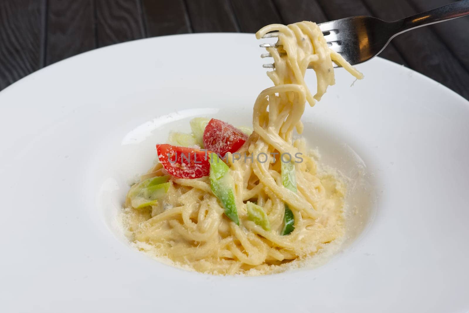 Plate with pasta served with bacon and ham, decorated with tomato cherry