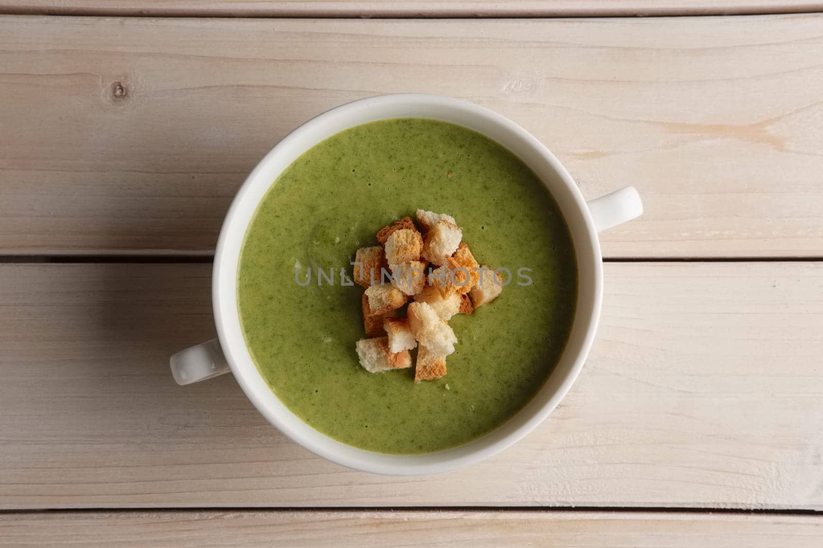 Plate of pea soup puree with crackers, top view
