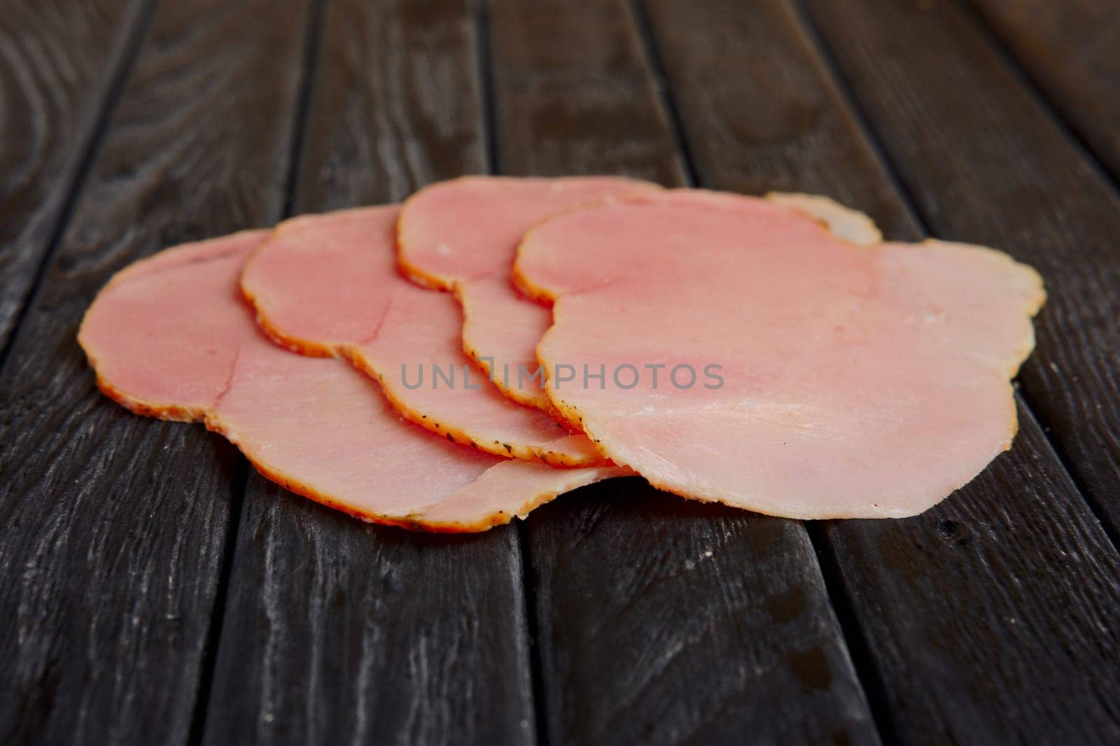 Selective focus photo of slices of fresh ham on wooden table.