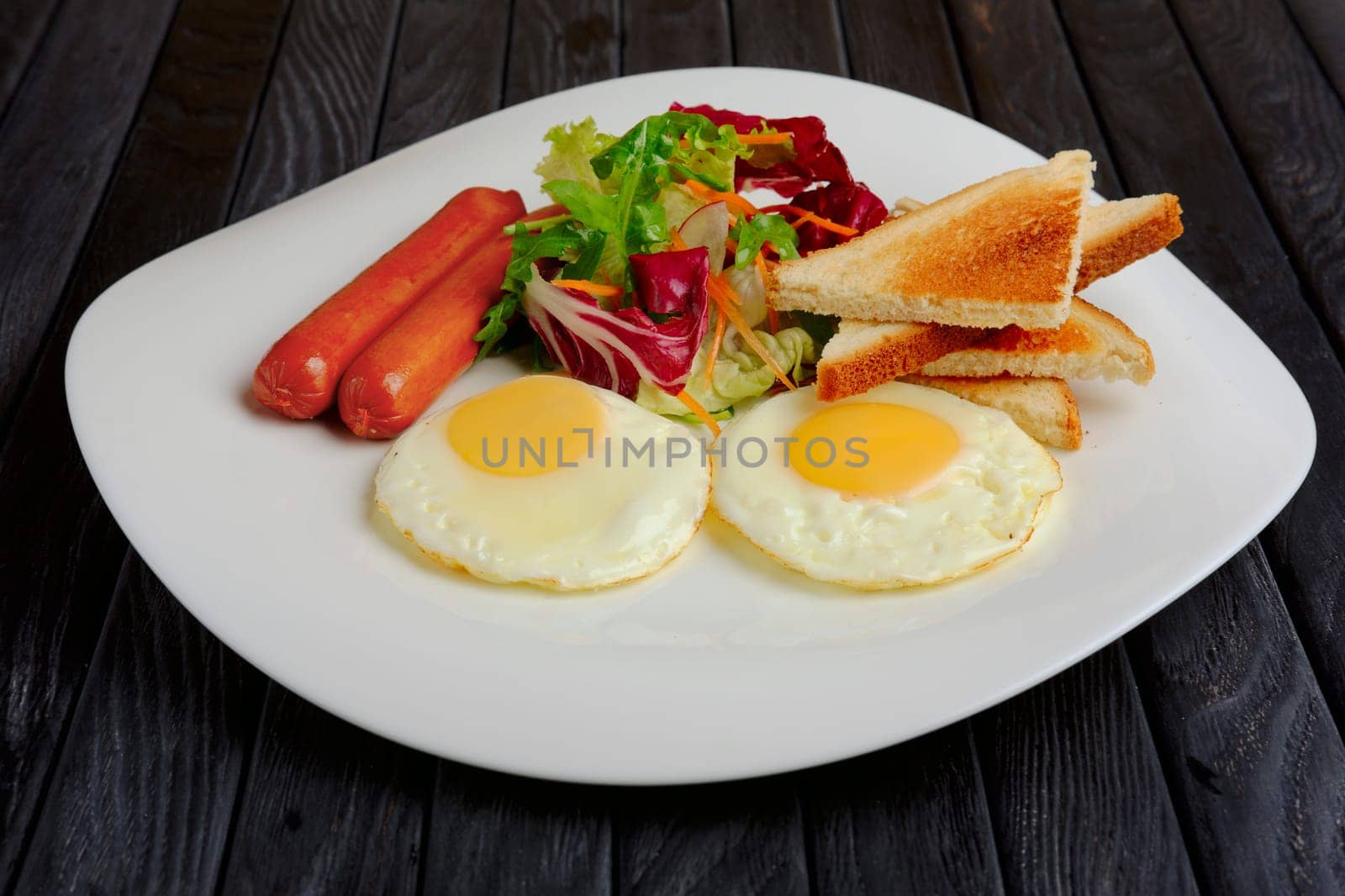 fried eggs with sausages, salad and toast