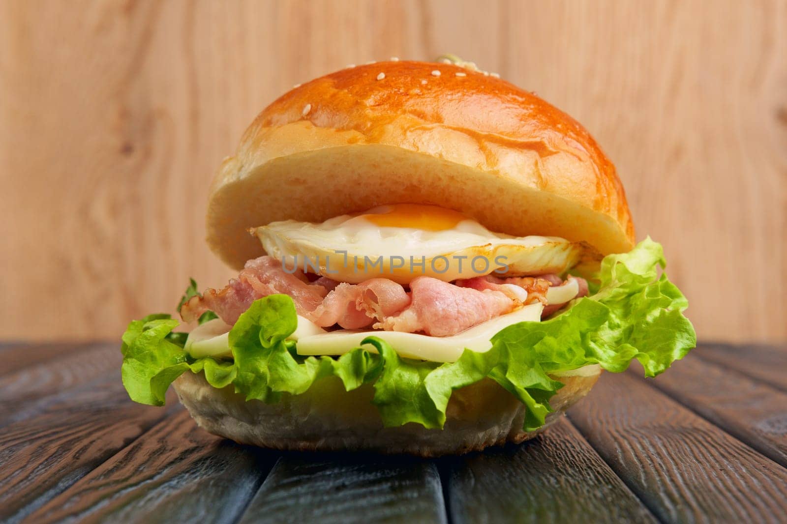 Tasty Egg burger with mozzarella, salad, and fried bacon