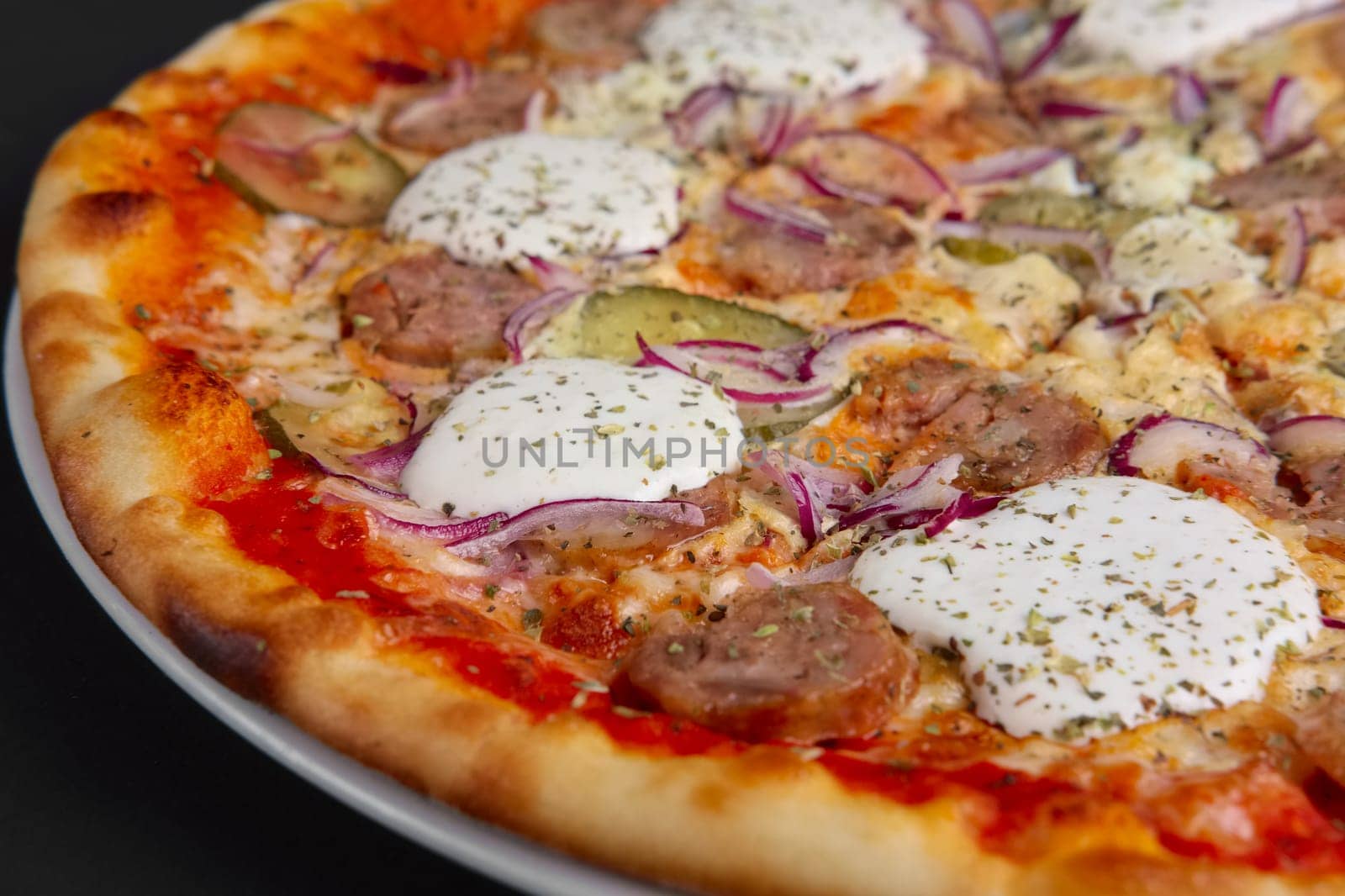 Closeup photo of pizza with sausage, pickled cucumber, onion and horseradish. Selective focus.