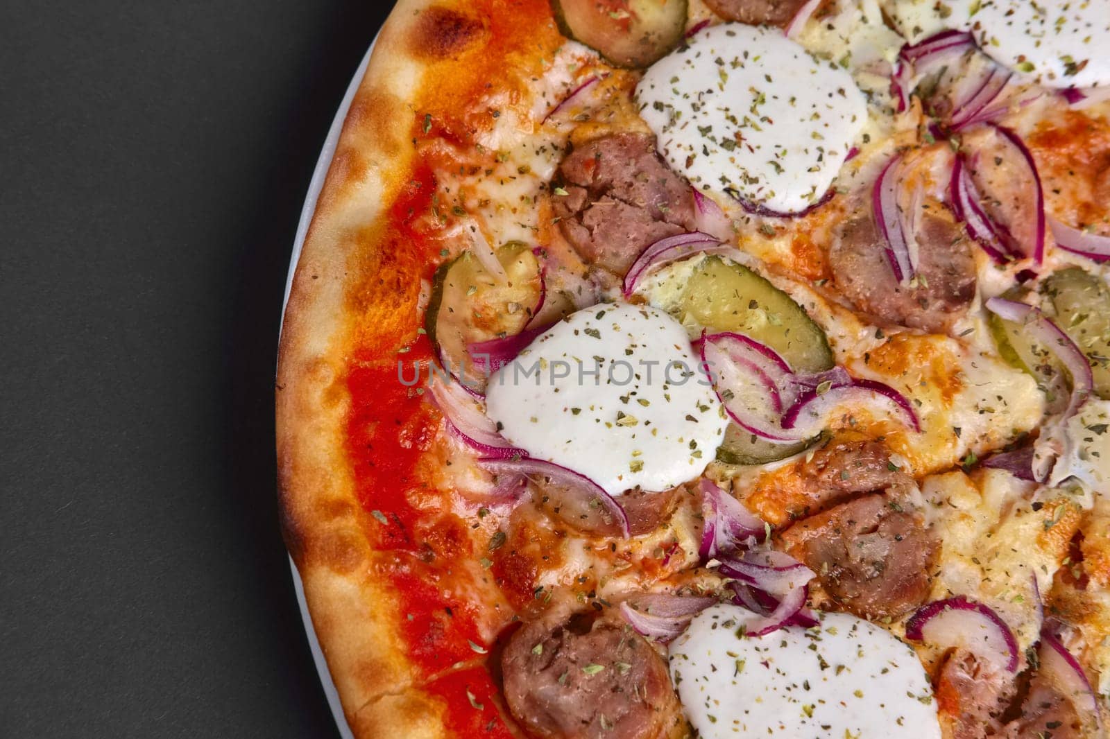Top view of pizza with sausage, pickled cucumber, onion and horseradish