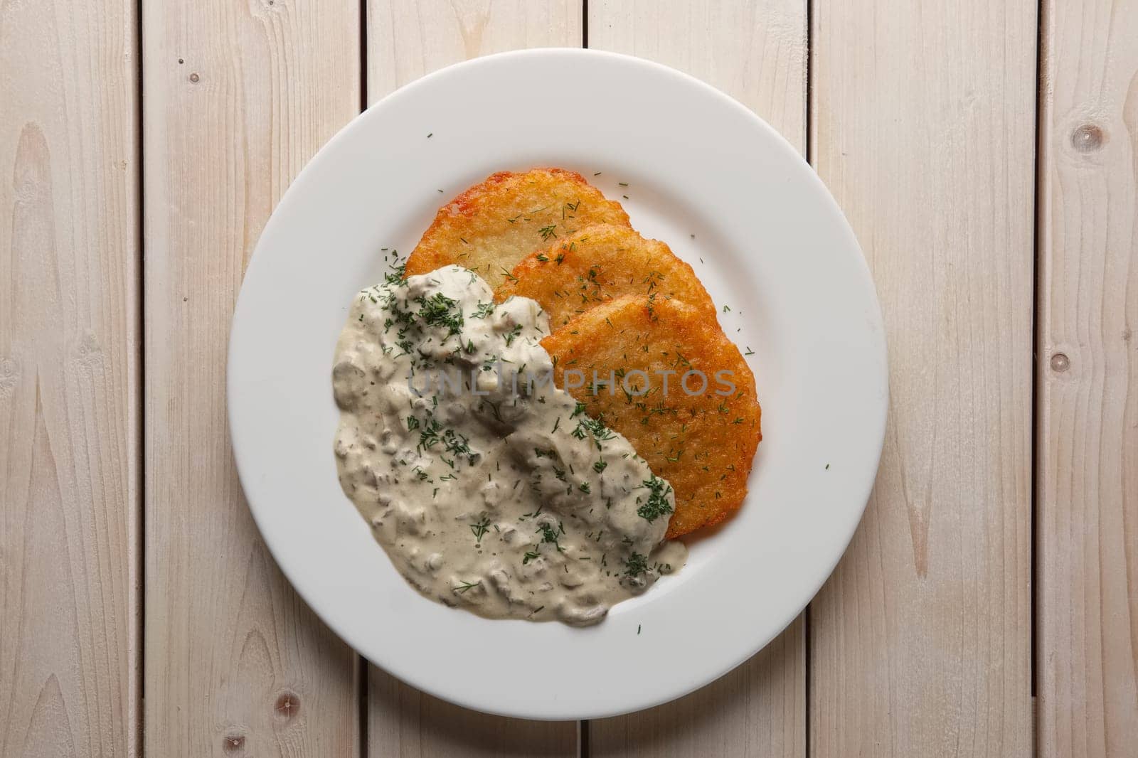 Traditional belorussian potato pancakes draniki with mushroom sauce on a plate