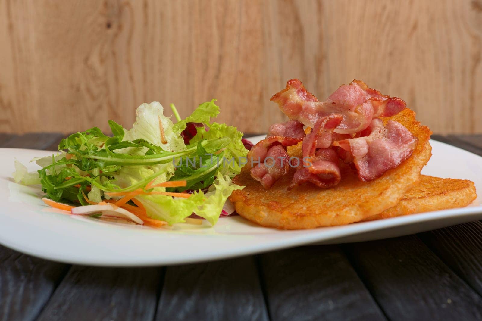 Traditional russian draniki with bacon and salad. Low angle view.