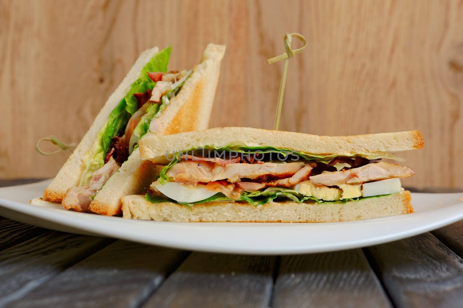 Plate with club sandwich on wooden table