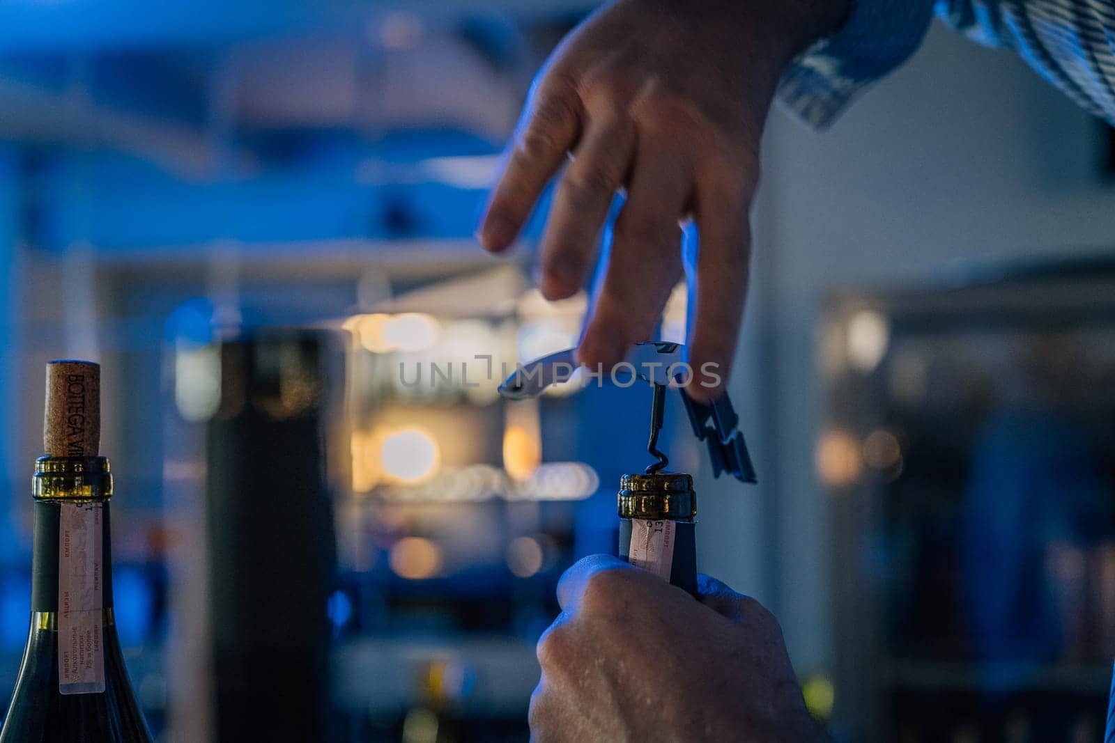 Hands of a sommelier opening a bottle of wine with a corkscrew
