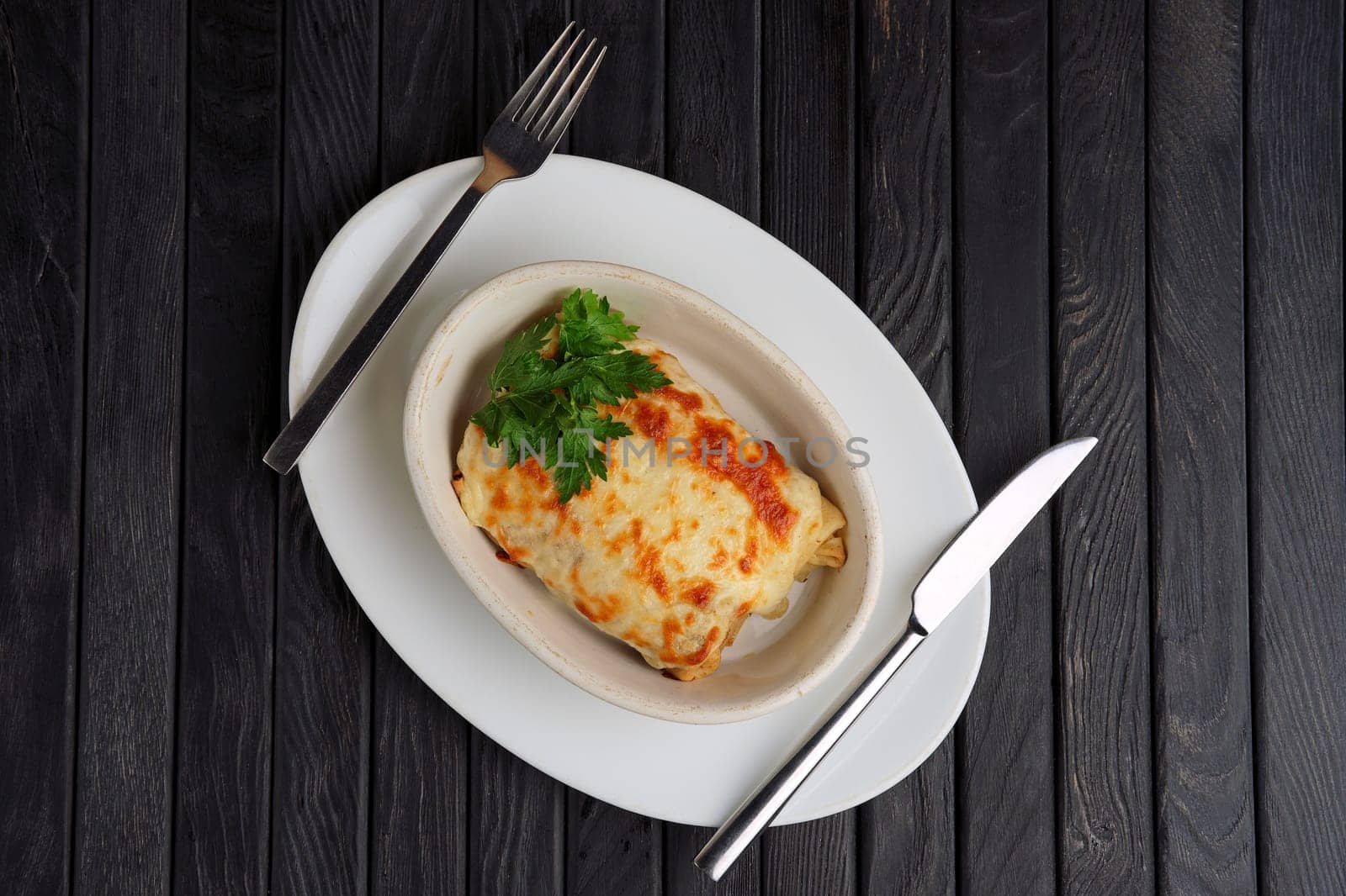 Top view of deep plate with pancakes covered with melted cheese.
