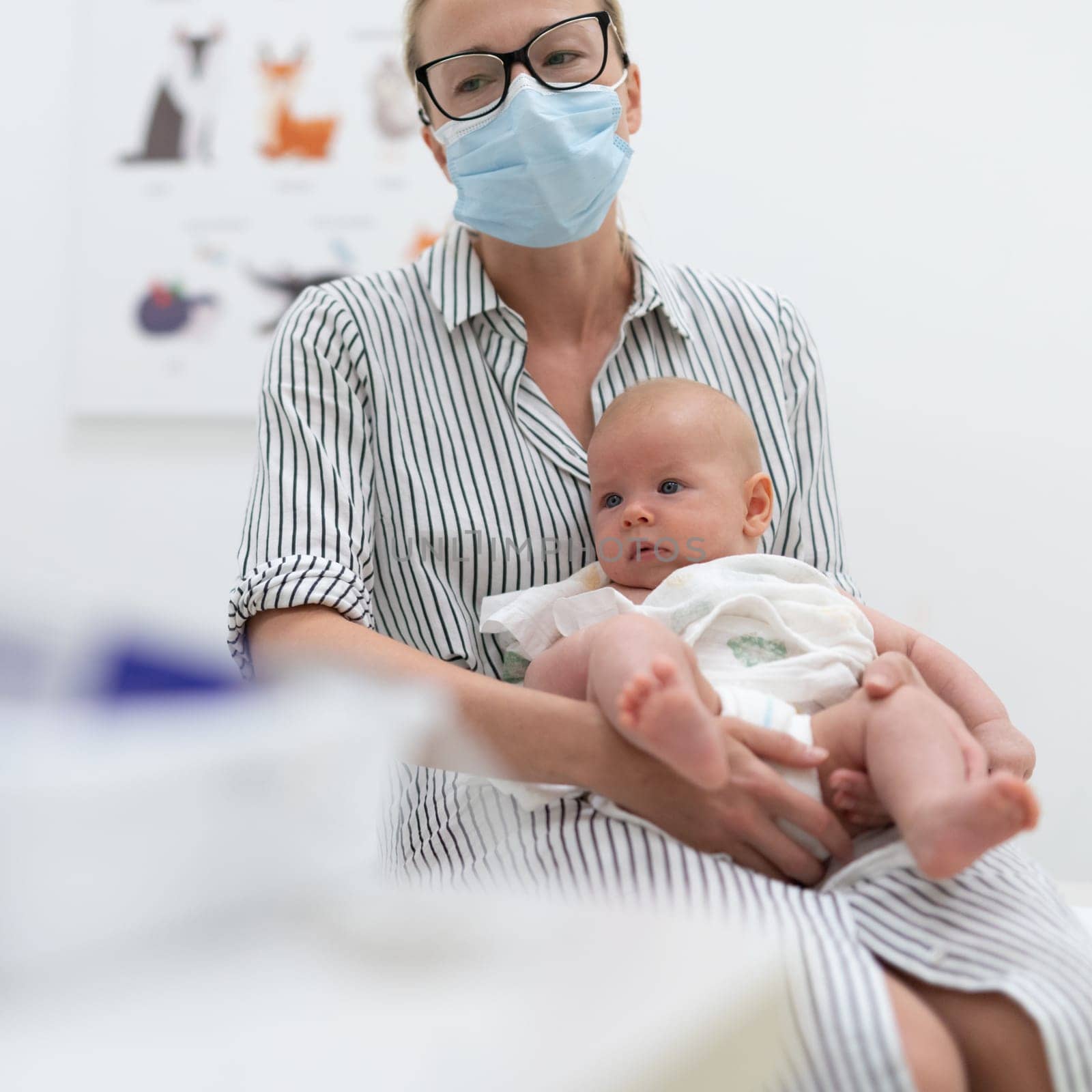 Mother holding her baby boy at medical appointment at pediatrician office