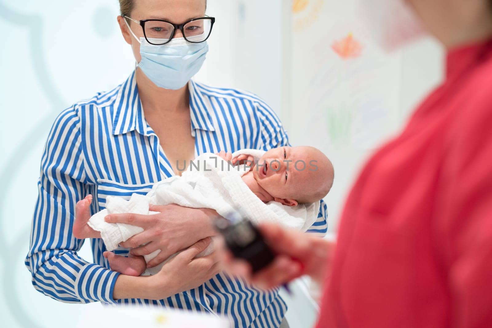 Mother holding her baby boy at medical appointment at pediatrician office