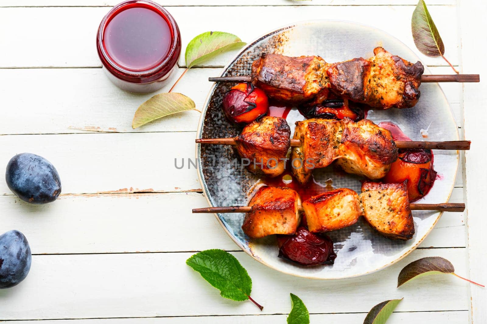 Fried meat on wooden skewers.Tasty kebabs in plum sauce