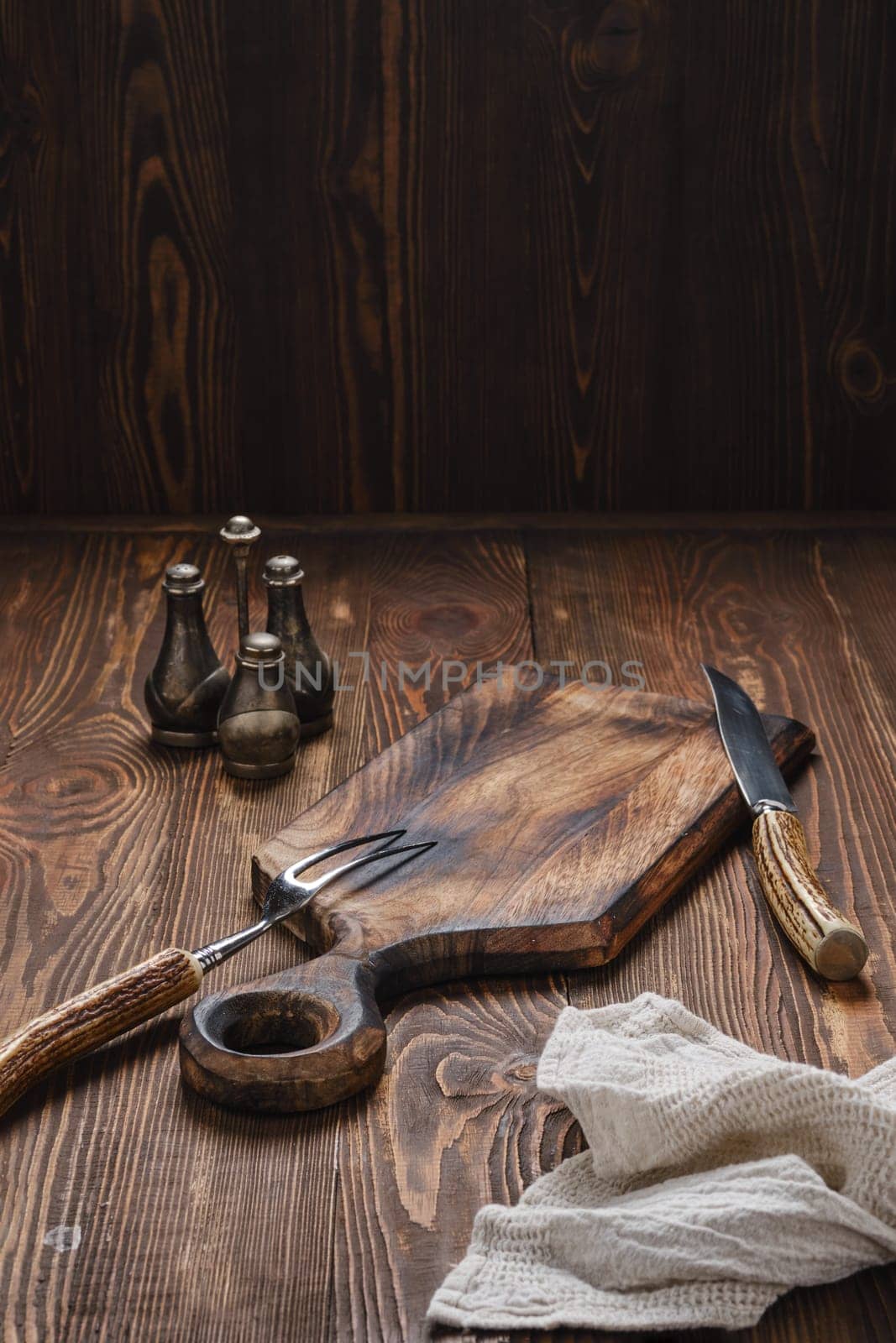 Empty wooden cutting board, fork and knife with for steak on rustic wooden table