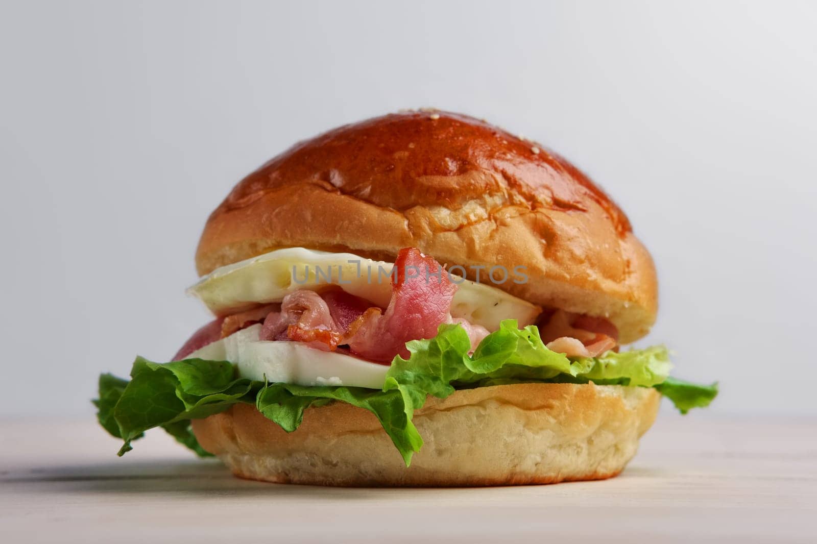 Soft focus photo of burger with mozzarella, bacon and fried egg.