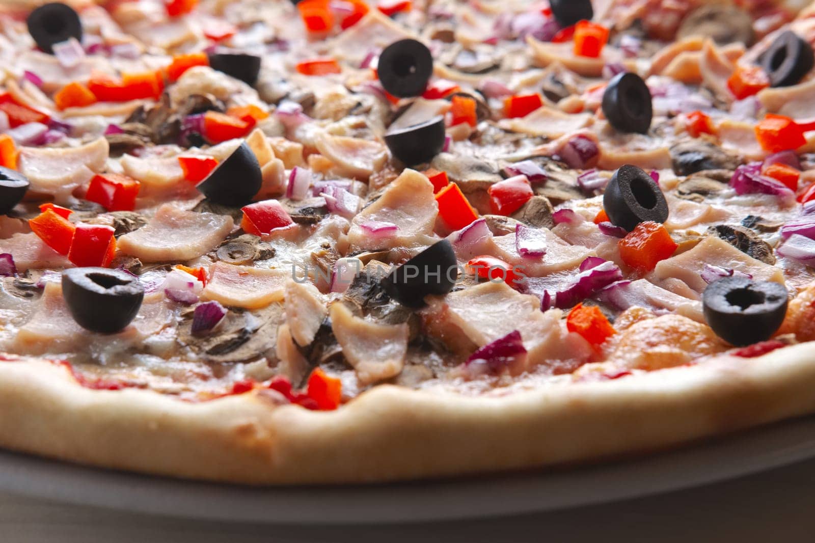 Close-up view of pizza with ham, olives, pepper and mushroom