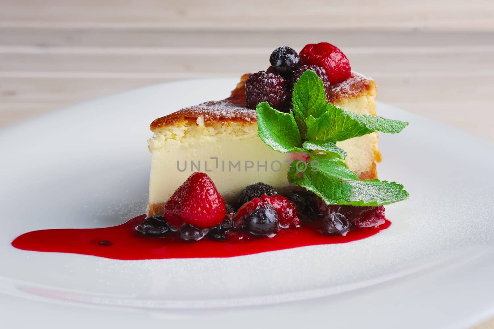 Cheesecake with berries sauce and green mint leaf.